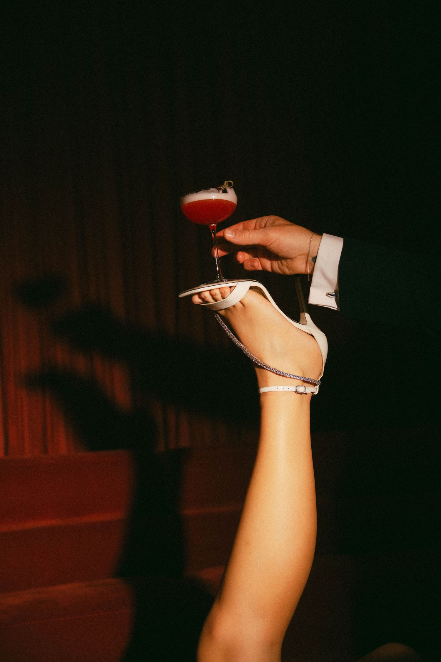 A sequence of photos showing a woman's hand holding a high heel shoe in different positions against a dark background.