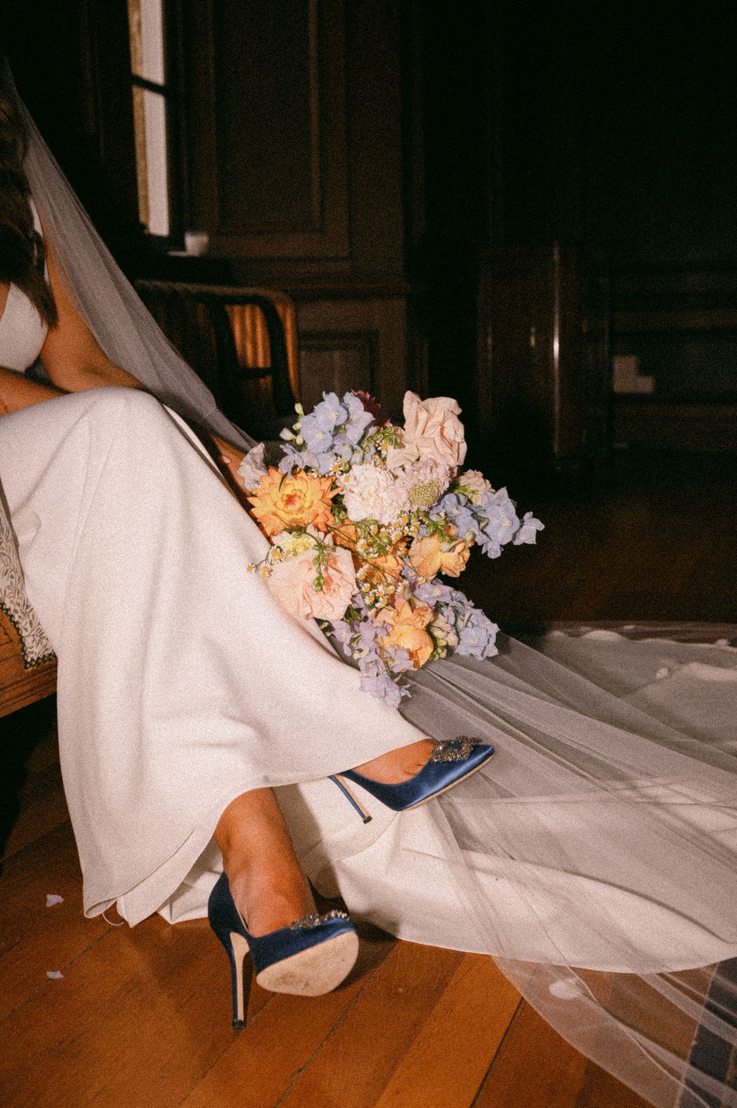 Detail shot of a bridal bouquet with blue and peach flowers next to white wedding dress and blue heels.  Aberdeen wedding photographer