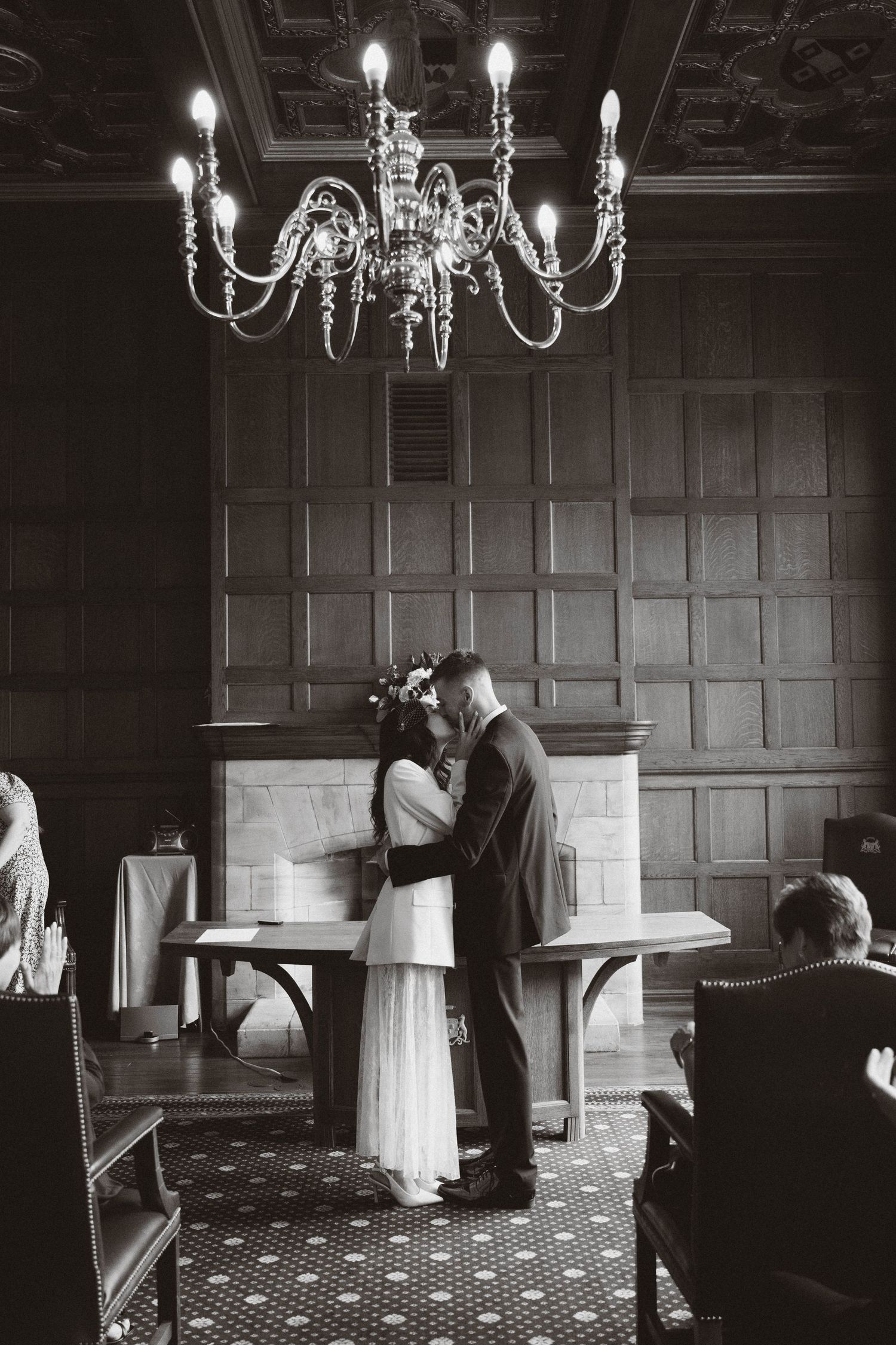 A sequence of four black and white wedding photos showing a couple dancing in an elegant wood-paneled room with chandeliers.