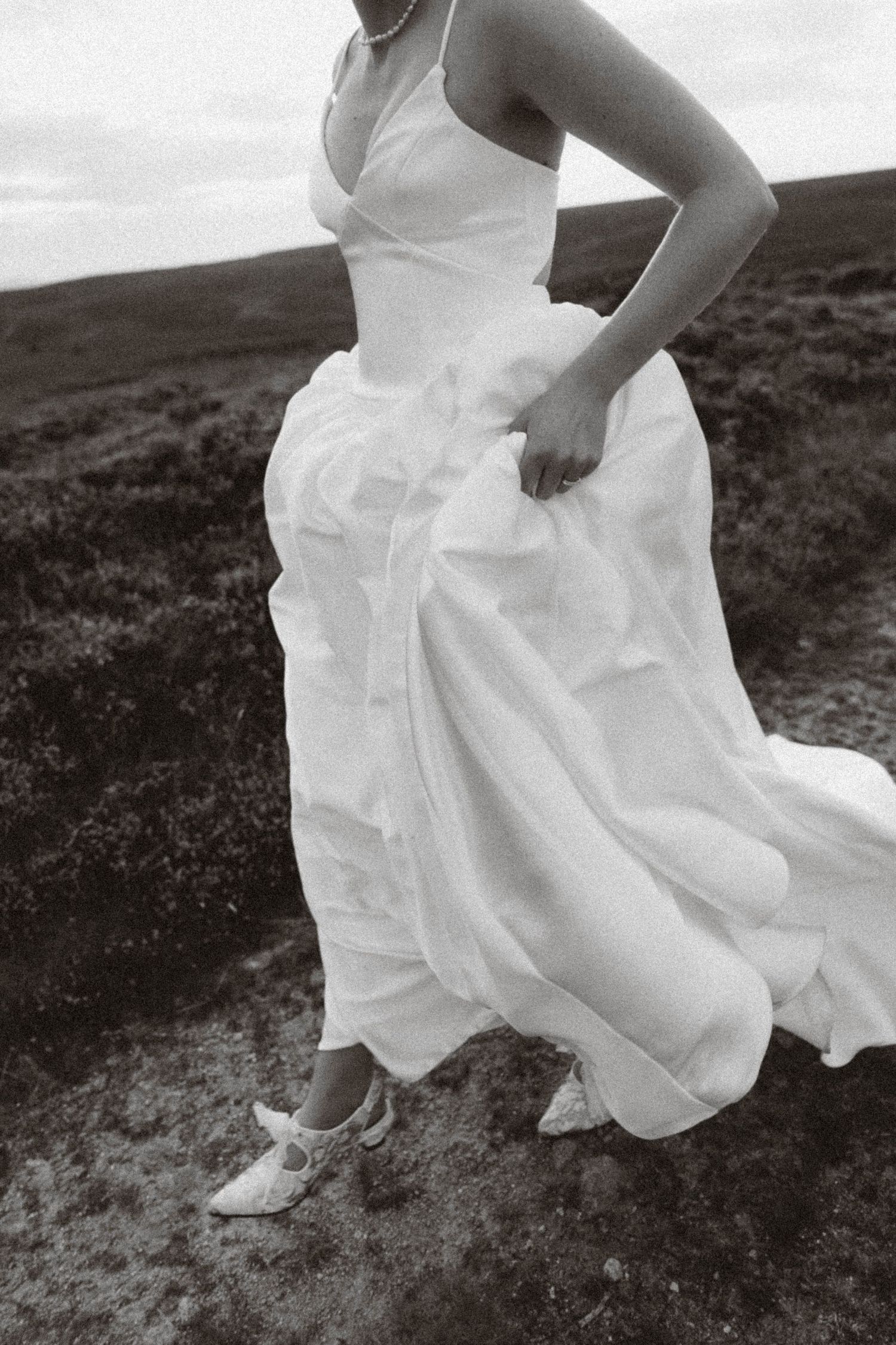 A sequence of black and white photos showing flowing white dress fabric and legs in motion across rugged terrain.