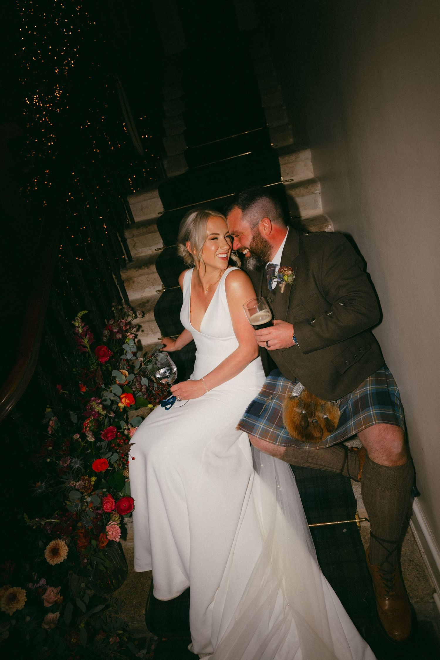 A romantic first dance sequence between newlyweds at a dimly lit wedding reception with red floral decorations.