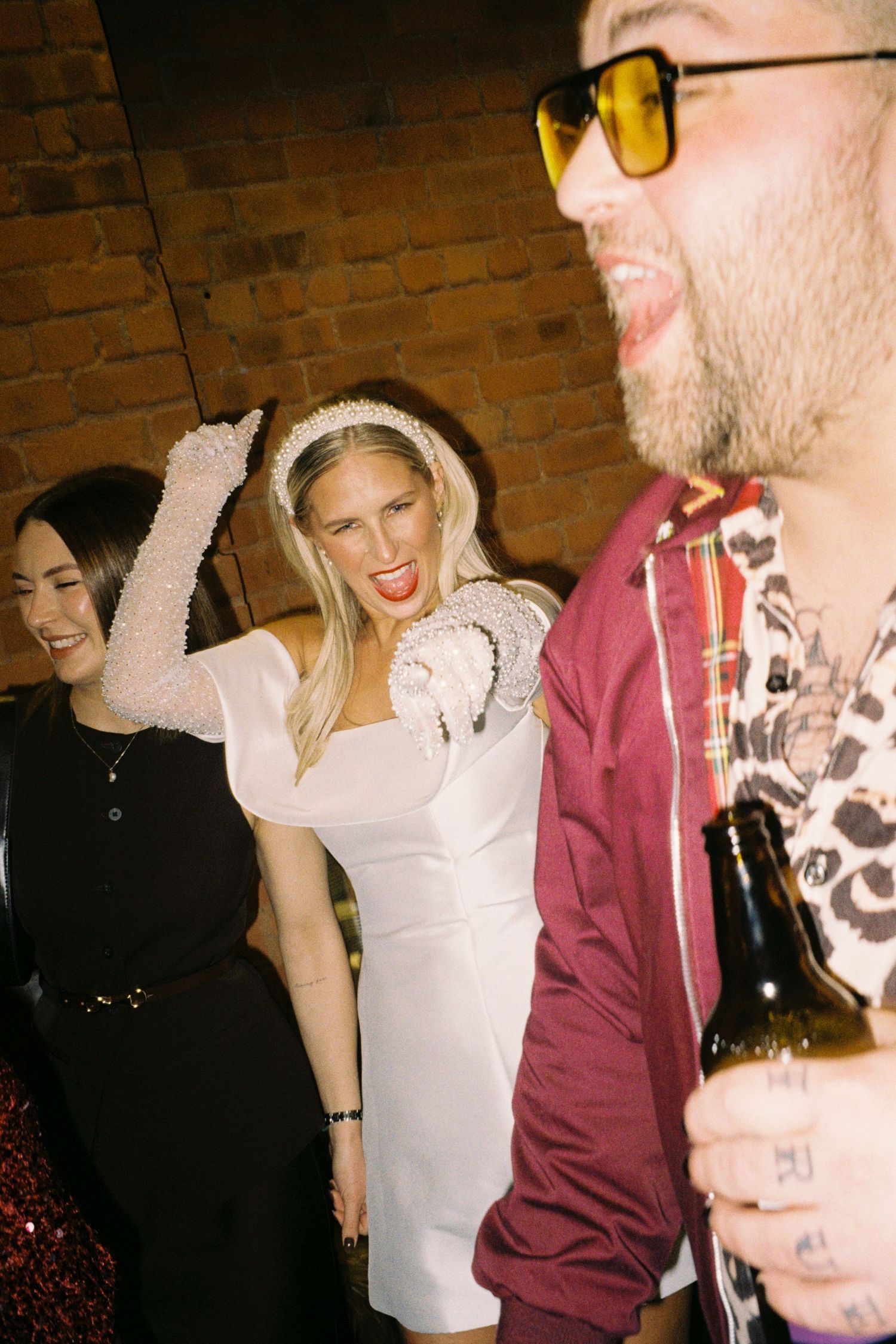 A group of people enjoying a social gathering in a brick-walled room with animated expressions and laughter.