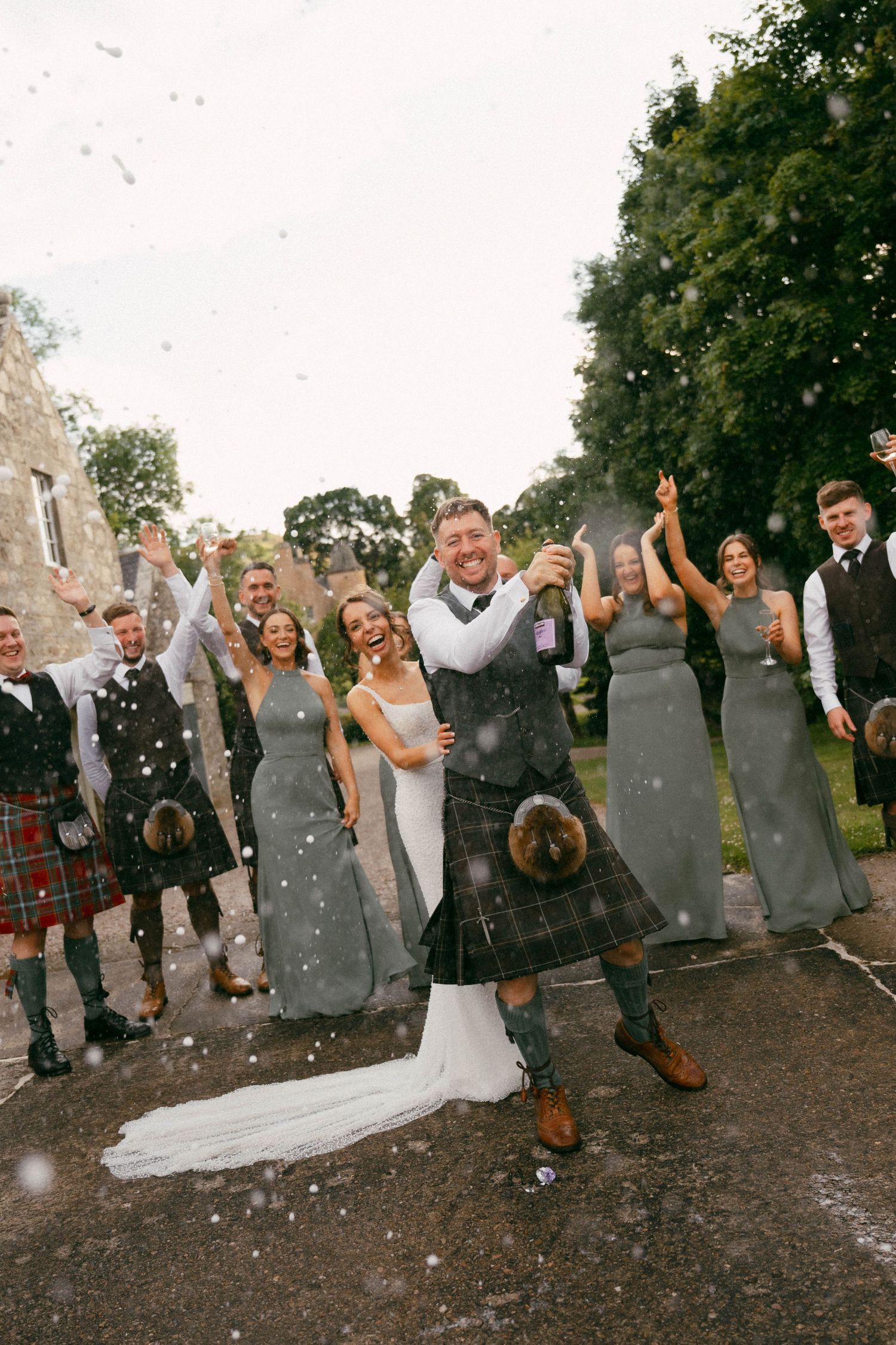 Wedding party stands together outdoors while throwing snow or confetti in a fun celebratory sequence of photos.
