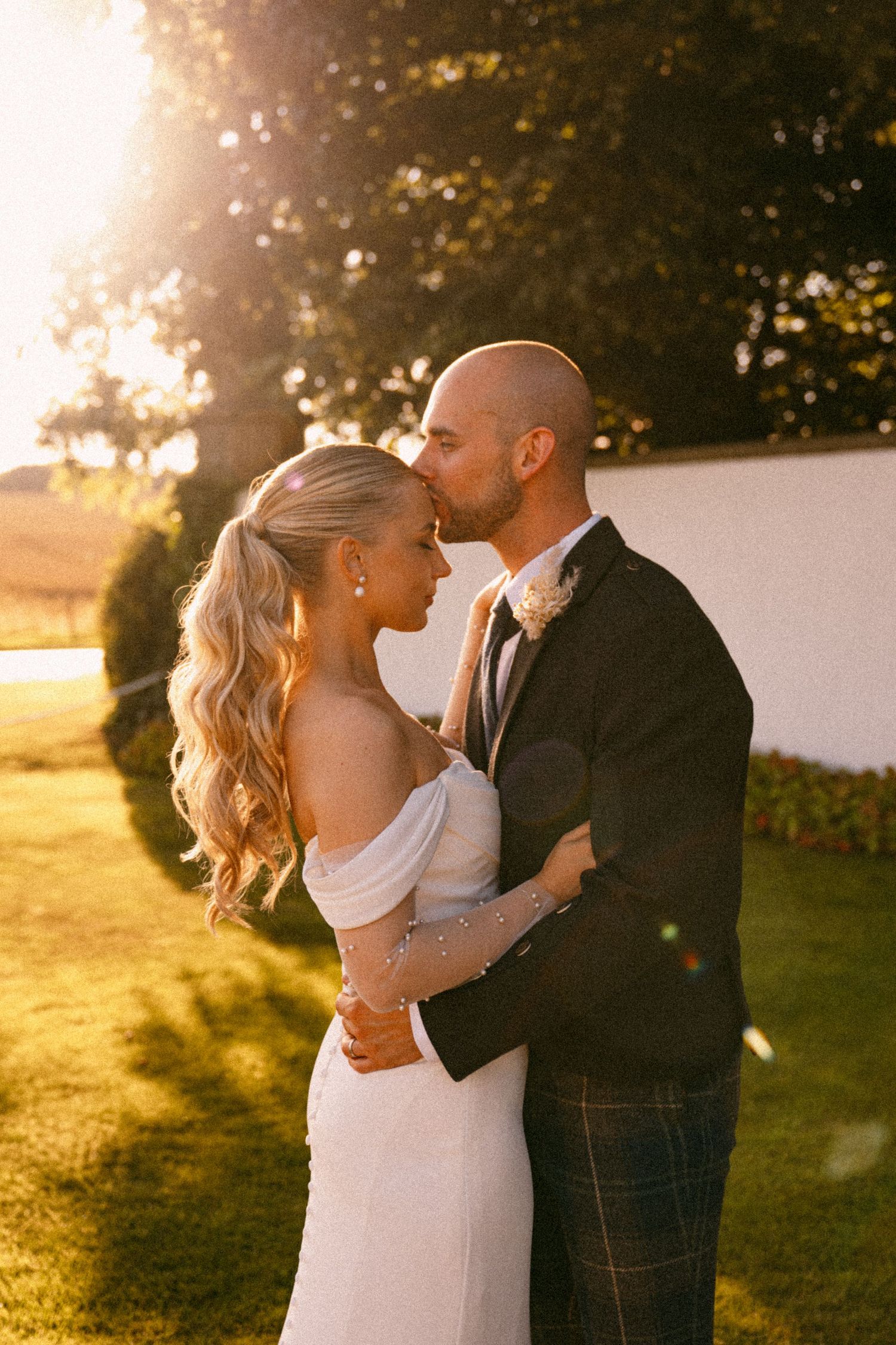 A romantic wedding couple embraces during golden hour sunset in a garden setting. Aberdeen wedding photographer, Meldrum House, golden hour
