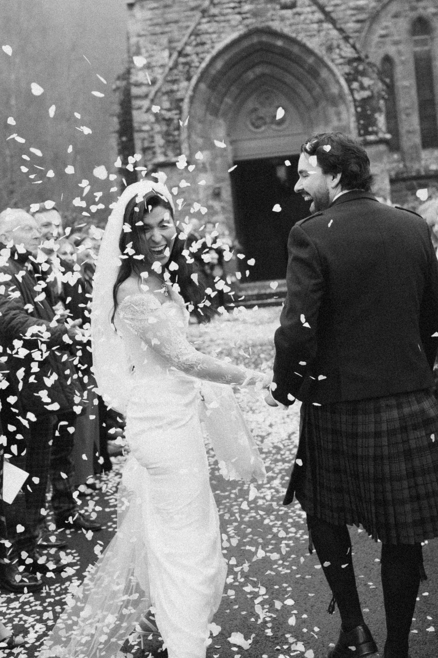 A wedding celebration outside a church with flower petals being thrown in the air.