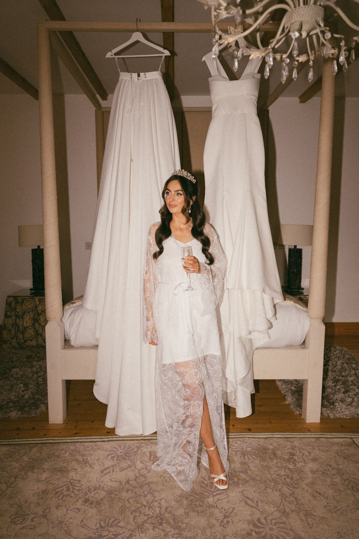 Wedding preparation scene with white gowns hanging from chandelier and person in lace robe. Aberdeen wedding photographer, achnagairn estate