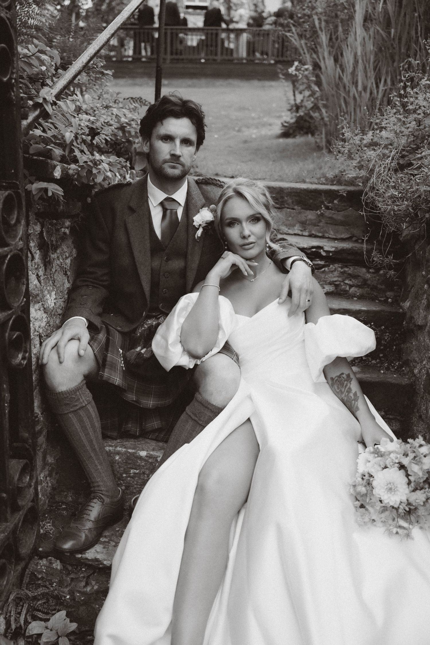 A black and white wedding photo series showing a playful couple posing outdoors in formal attire.