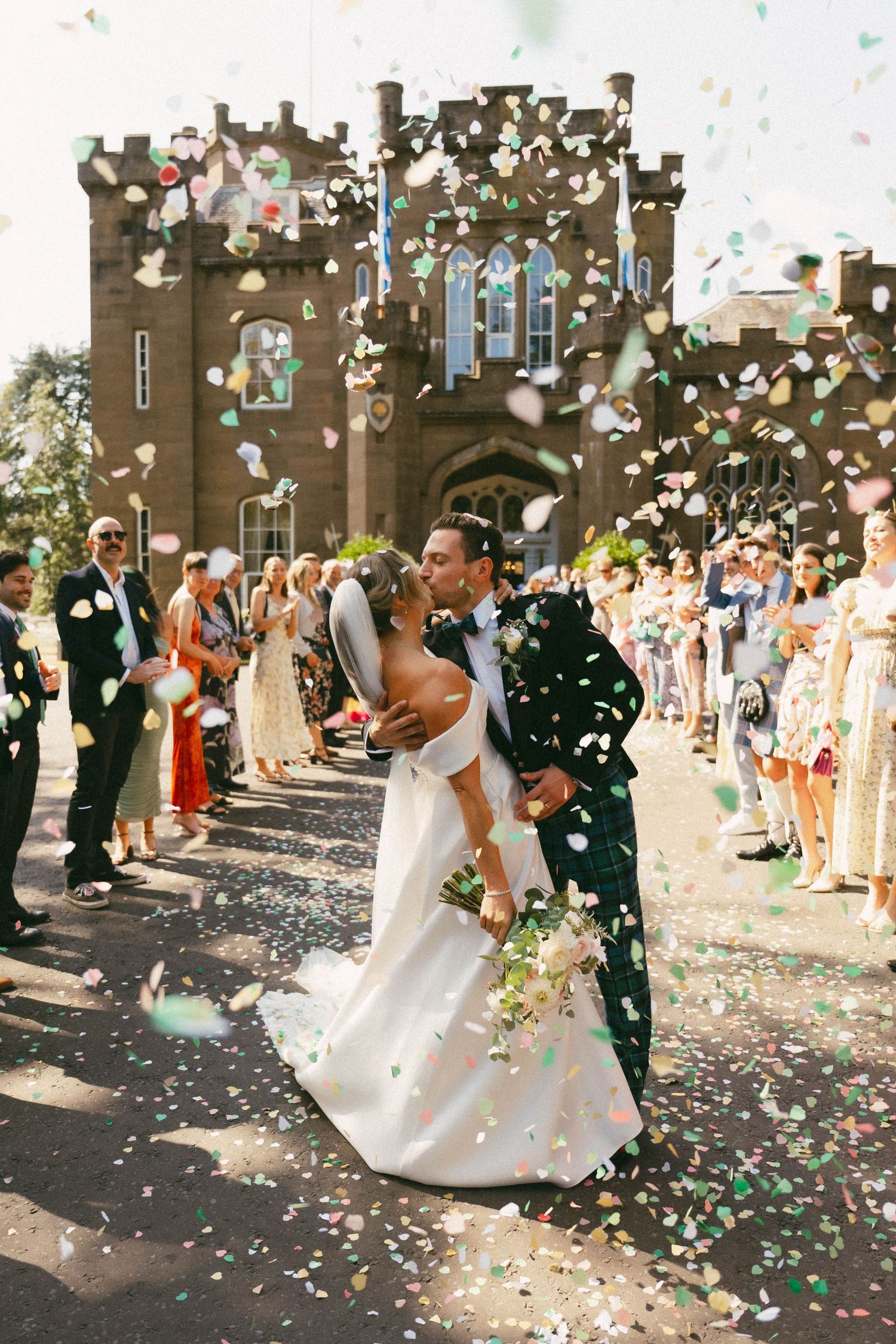 A joyful wedding celebration as confetti rains down on a couple dancing and twirling in front of a church.