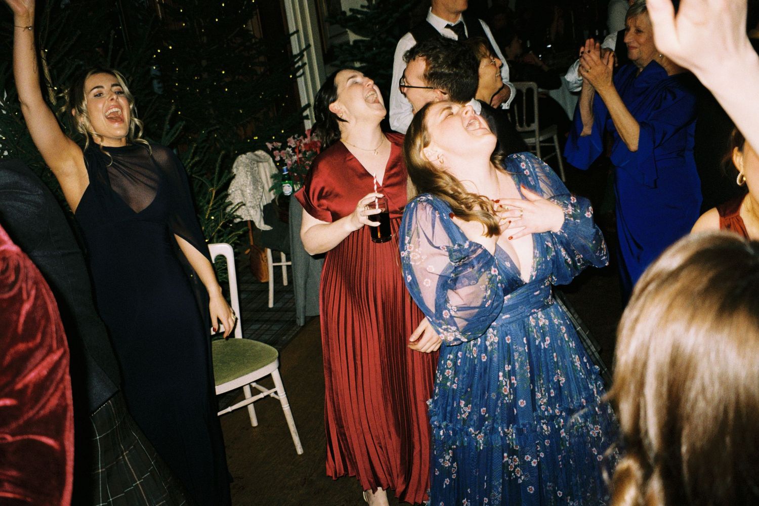 People dancing and celebrating at a formal event in burgundy and blue dresses.