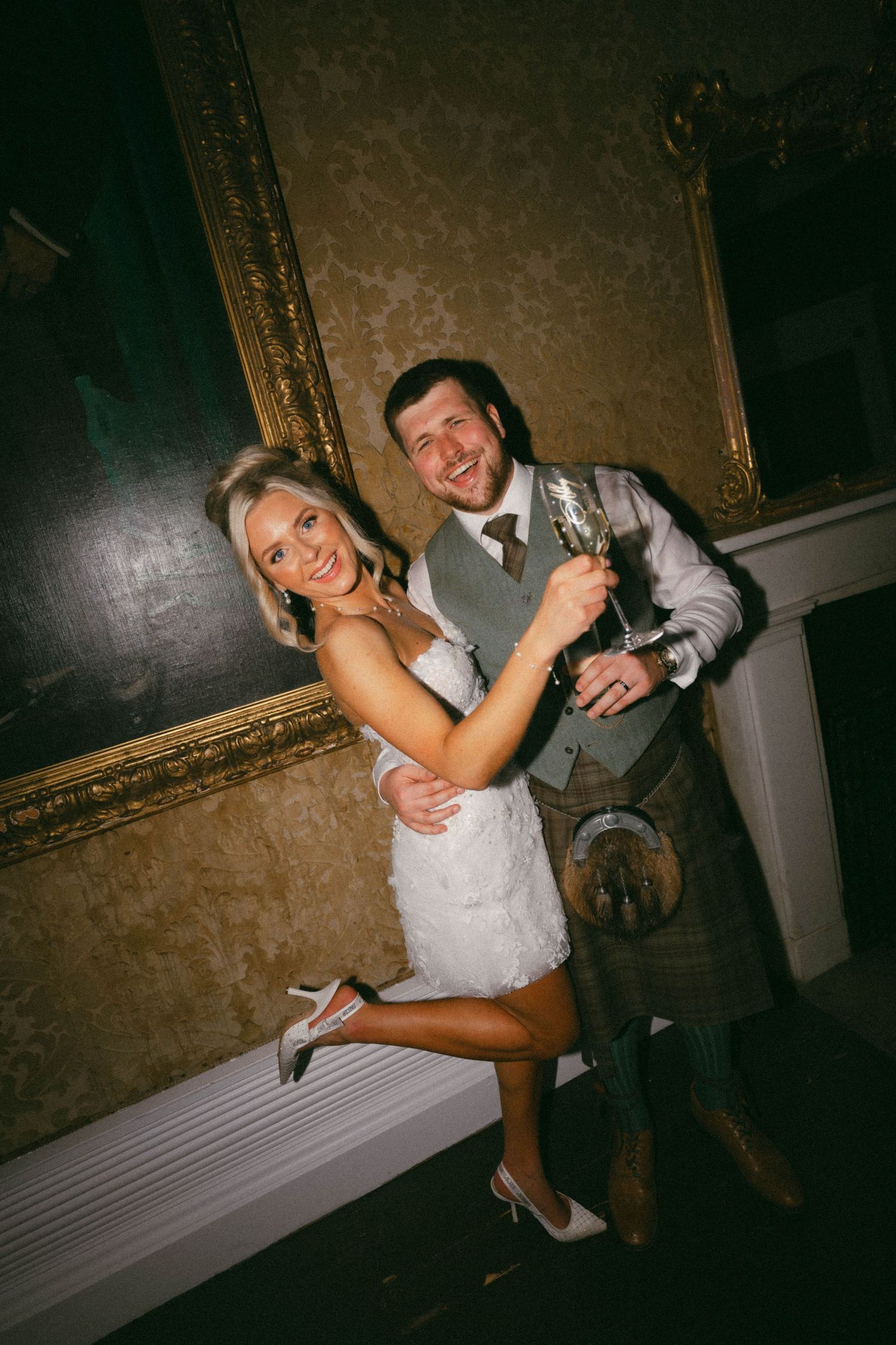 A wedding couple poses playfully on a staircase in a dimly lit venue with vintage decor.