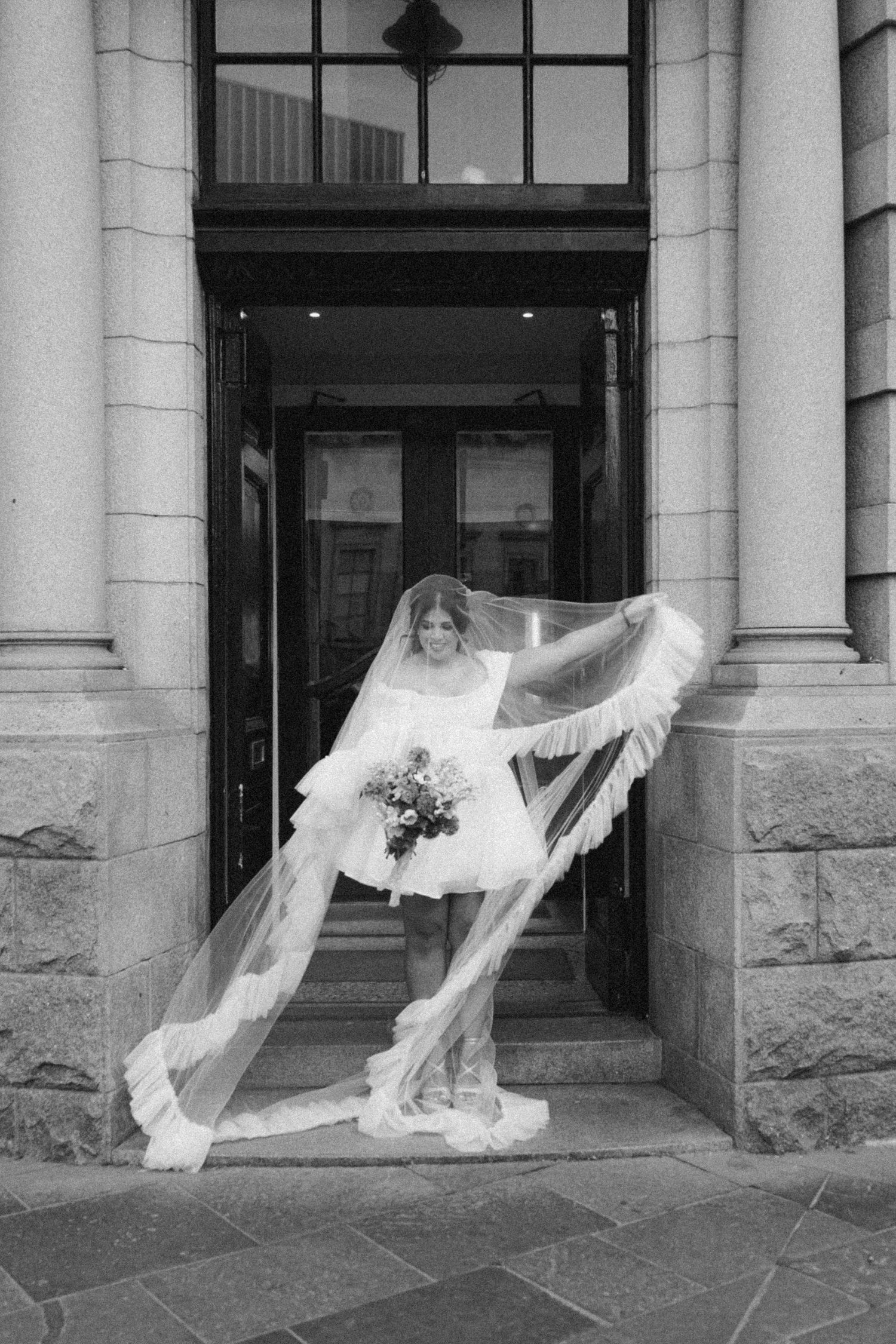 Dramatic shot of a flowing wedding veil blowing in the wind. Under the veil. Black and white. Scottish Wedding Photographer. City elopement