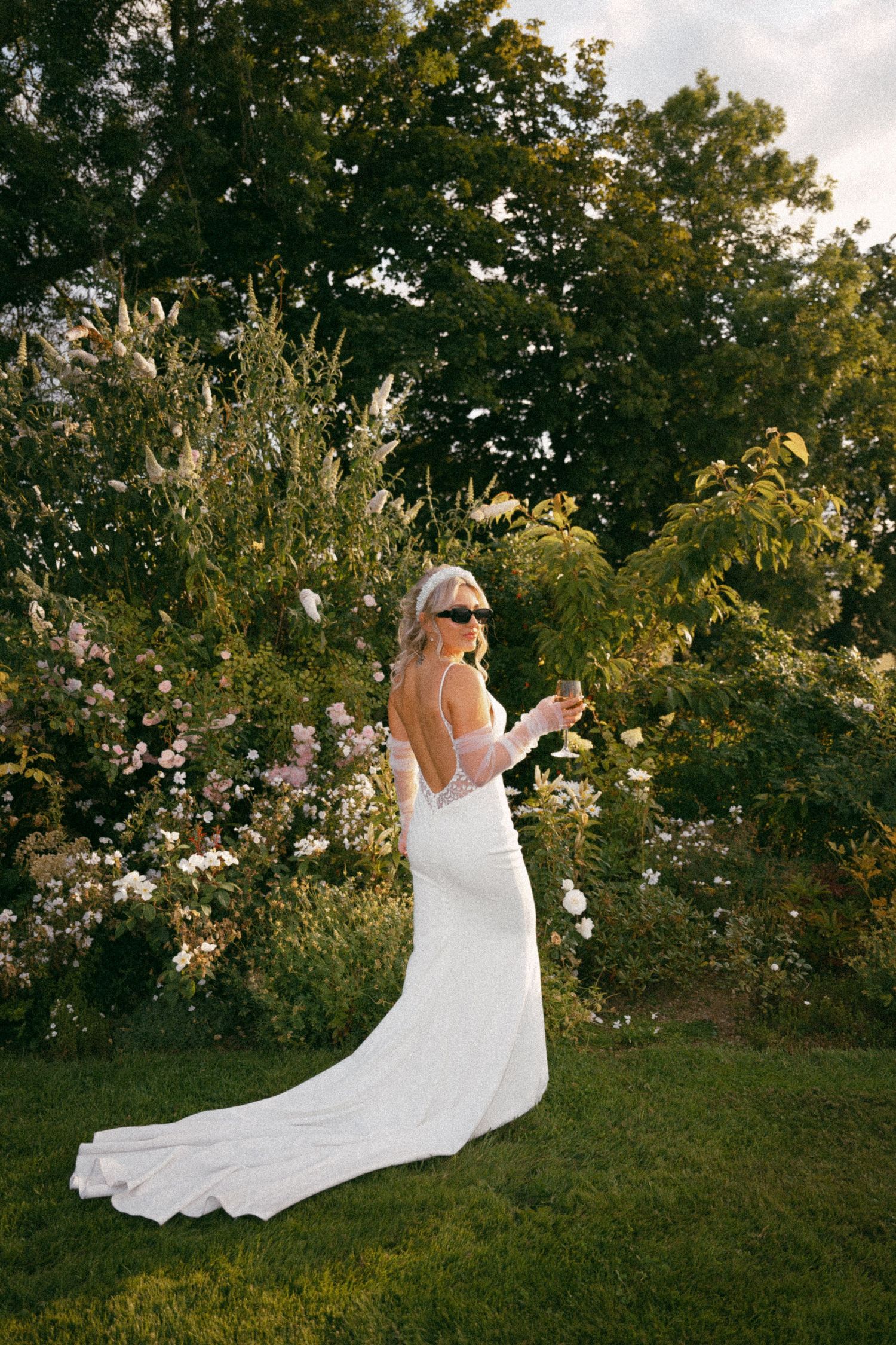 Elegant bride in backless white dress poses in garden wearing sunglasses. Aberdeen wedding photographer, Barra barn, golden hour wedding
