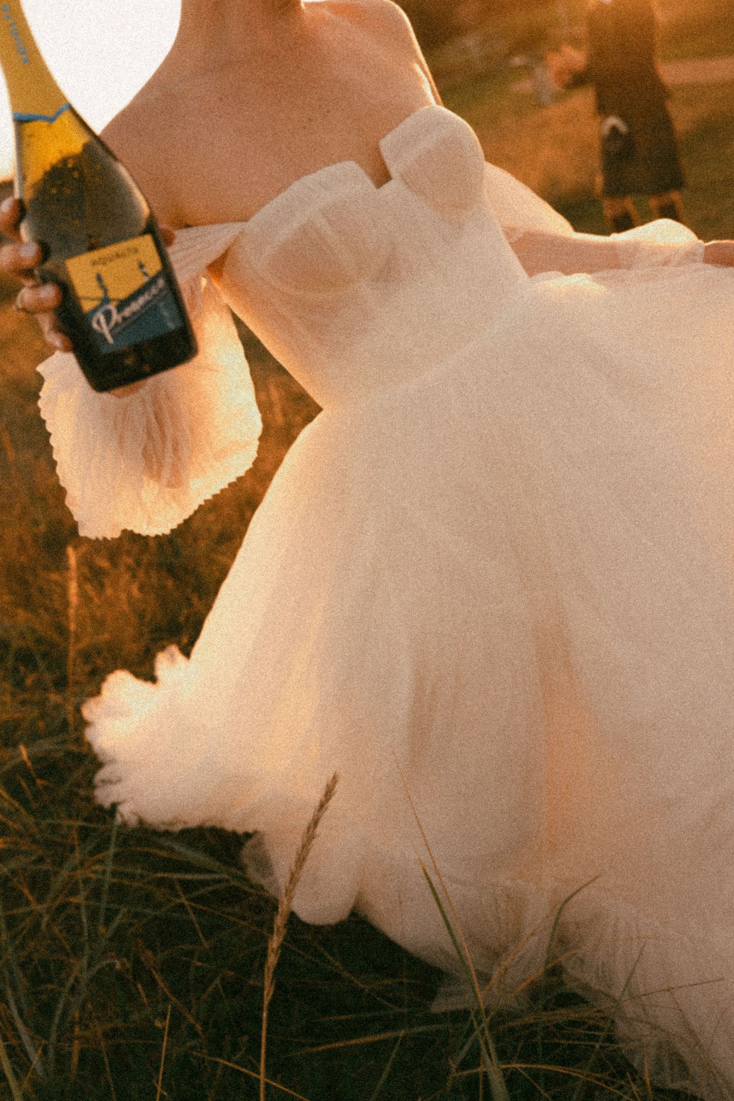 Close-up of tulle wedding dress skirt at golden hour with wine bottle.  Aberdeen wedding photographer,  carlogie house