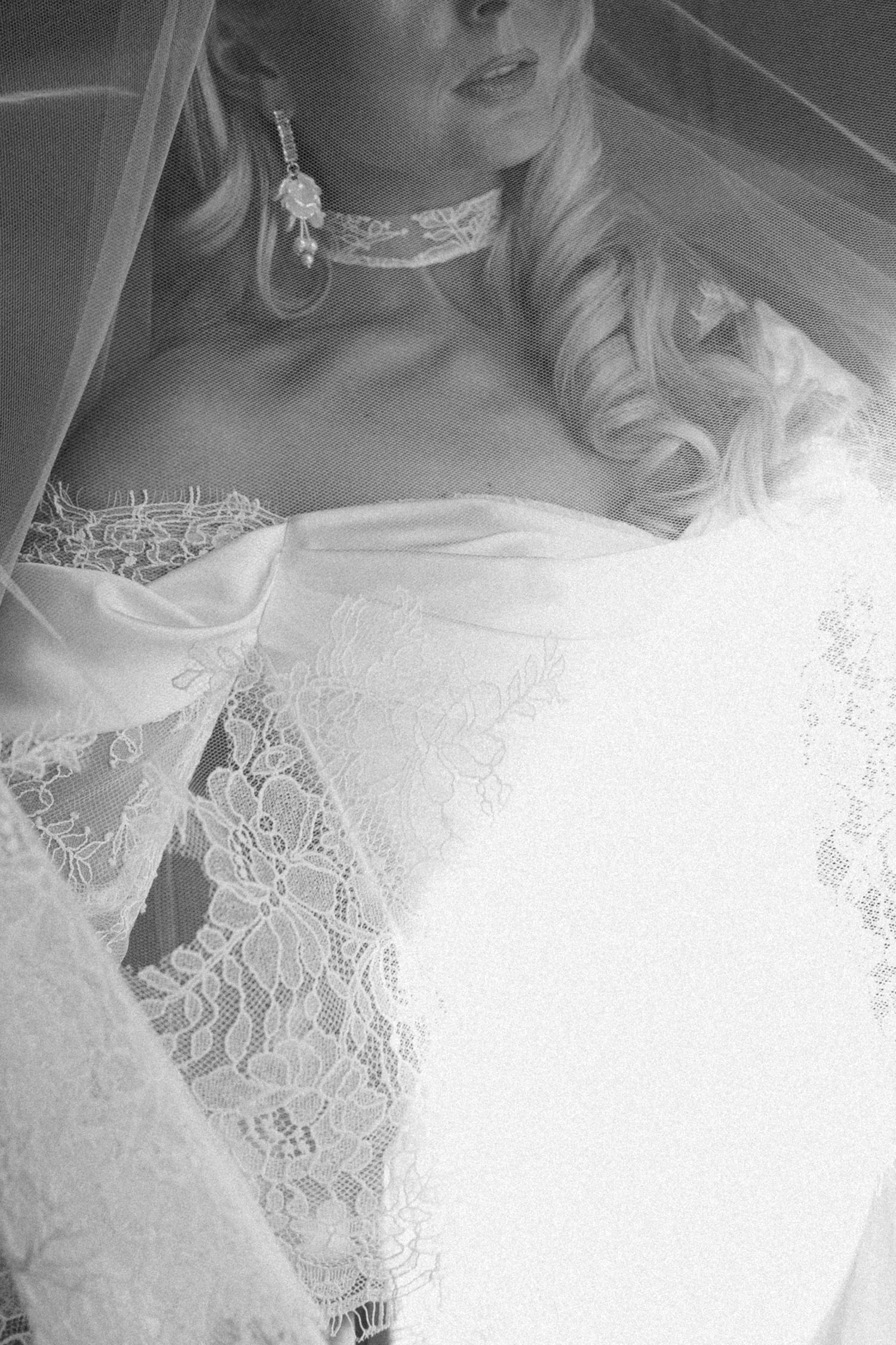 Close-up black and white detail of lace wedding dress bodice and veil.