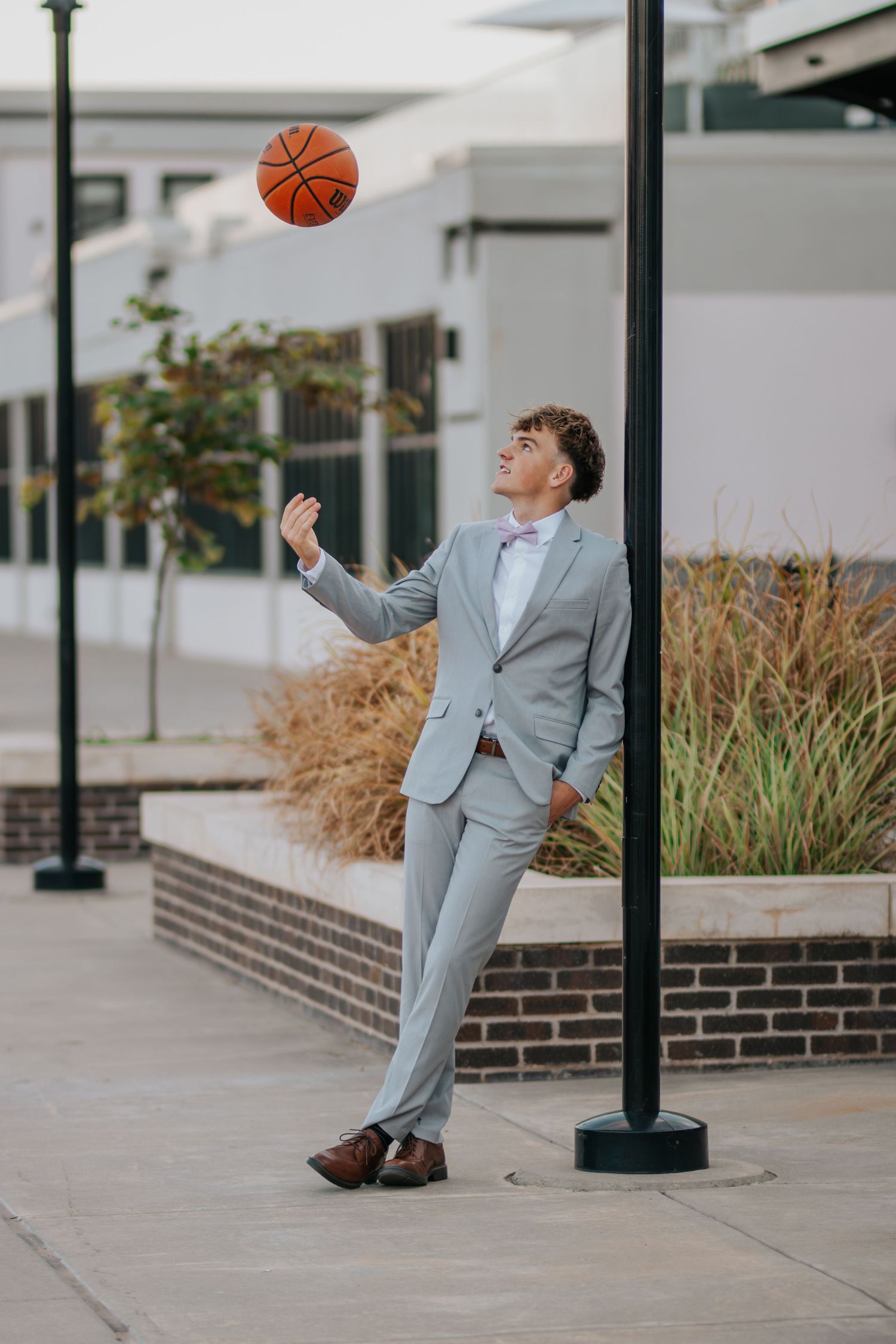 Person in gray suit playfully poses with basketball in urban setting across multiple connected photos.