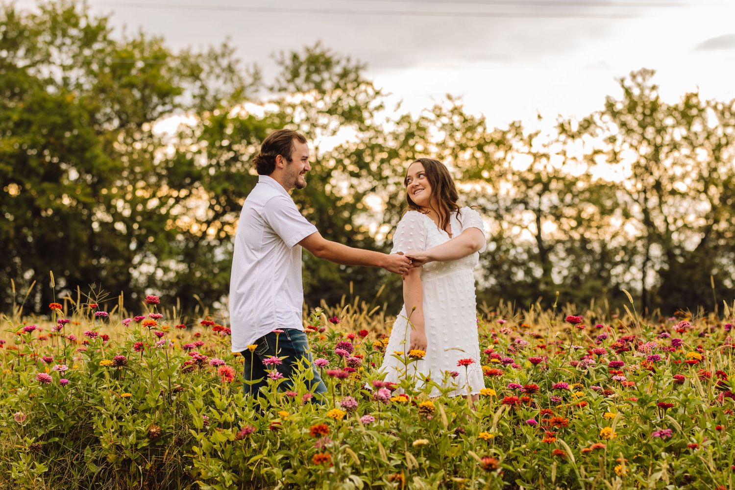 Couple dancing together in a vibrant field of red and yellow flowers at sunset.