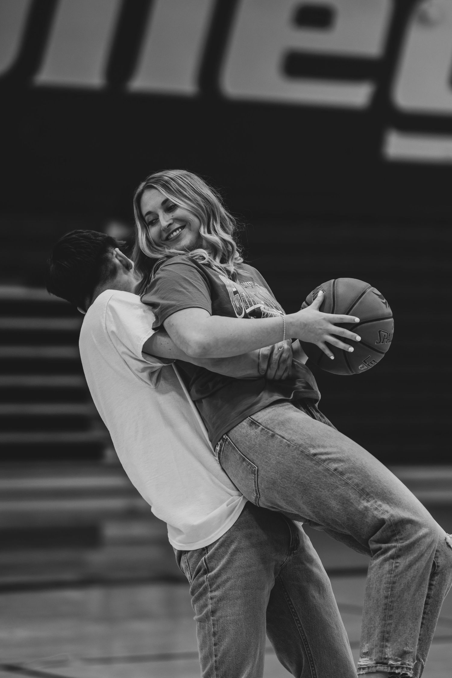 Black and white photo of a couple playing with a basketball in an indoor court.