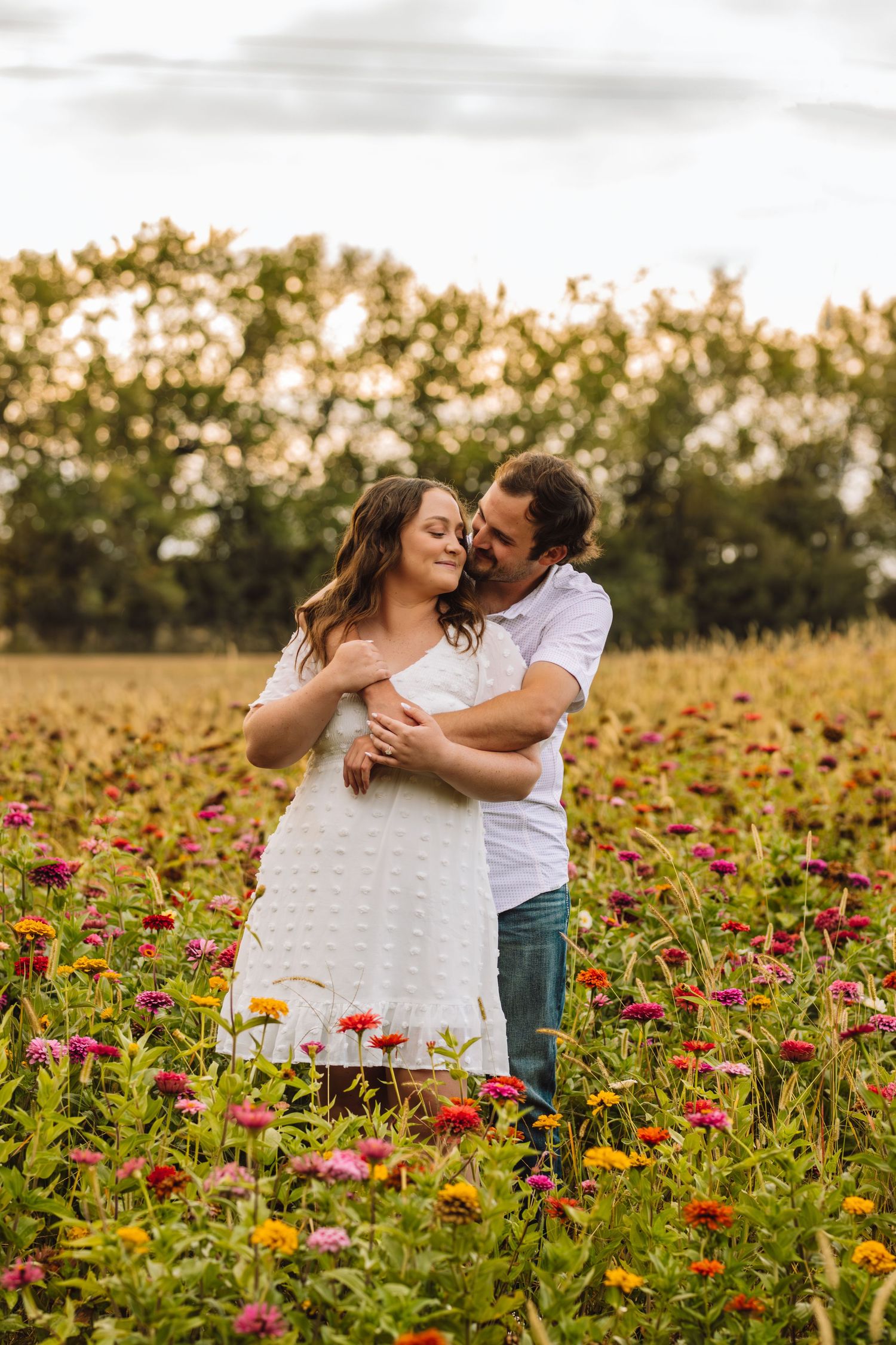 Intimate embrace captured in a field of colorful wildflowers during golden hour.