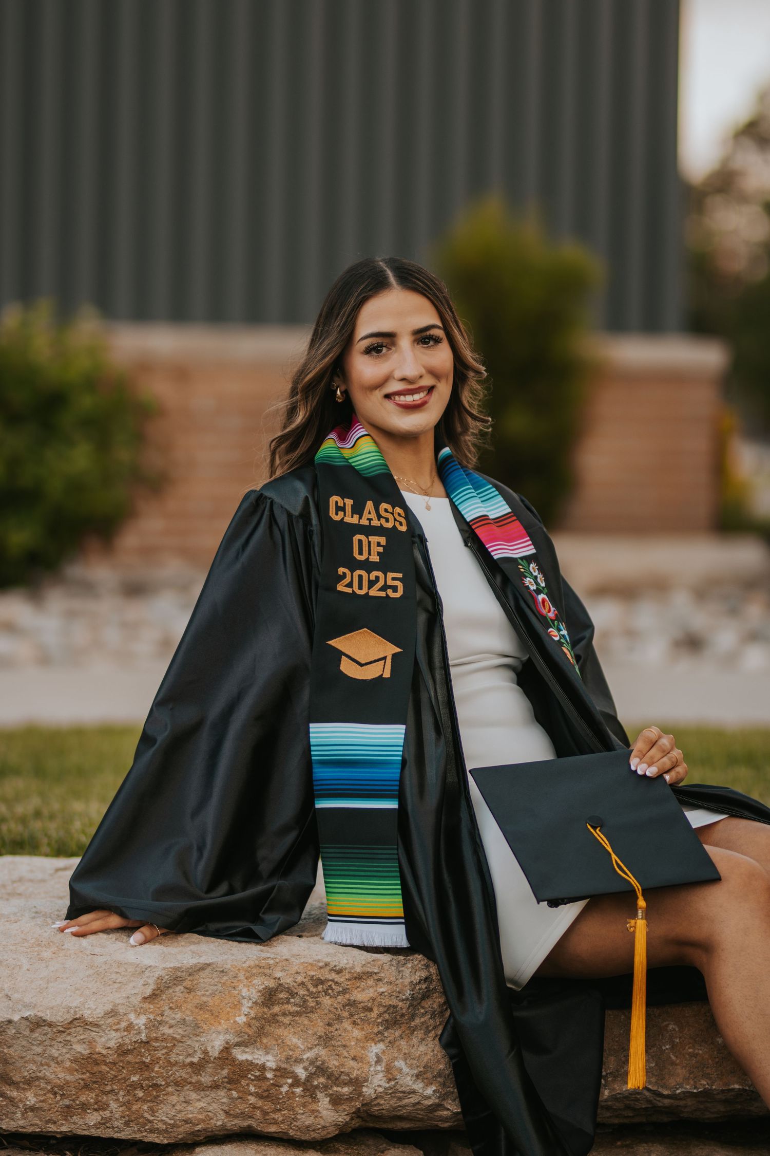 Graduation portrait series showing details of black cap and gown with colorful Class of 2025 decorations against natural outdoor setting.
