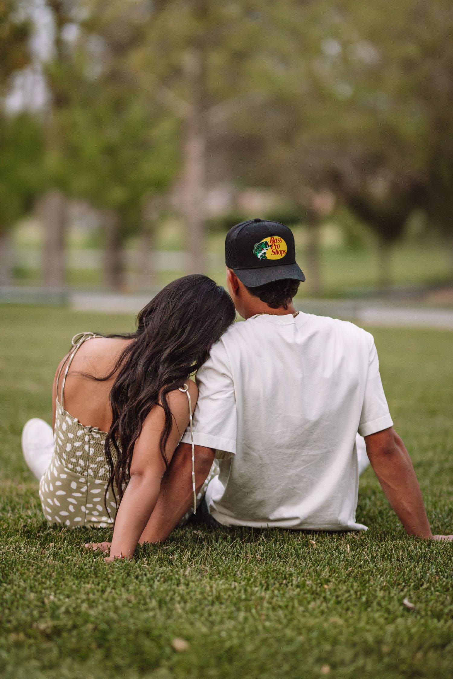 A couple relaxes together lying on grass in the park on a sunny day.