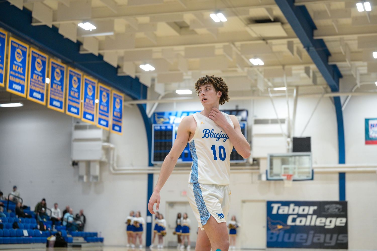 Basketball player in white jersey number 10 prepares to make a play on court.