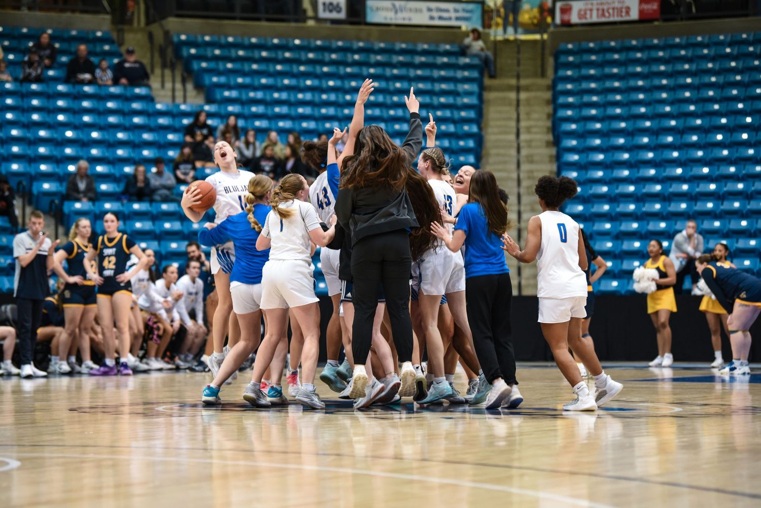 Basketball team celebrates victory with group huddle on court.
