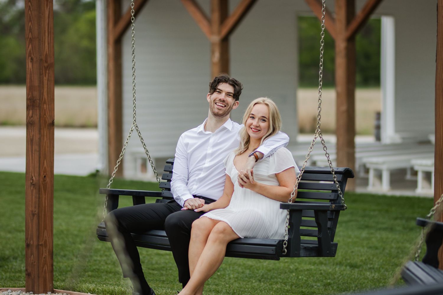 A couple shares a joyful moment while sitting together on an outdoor porch swing.