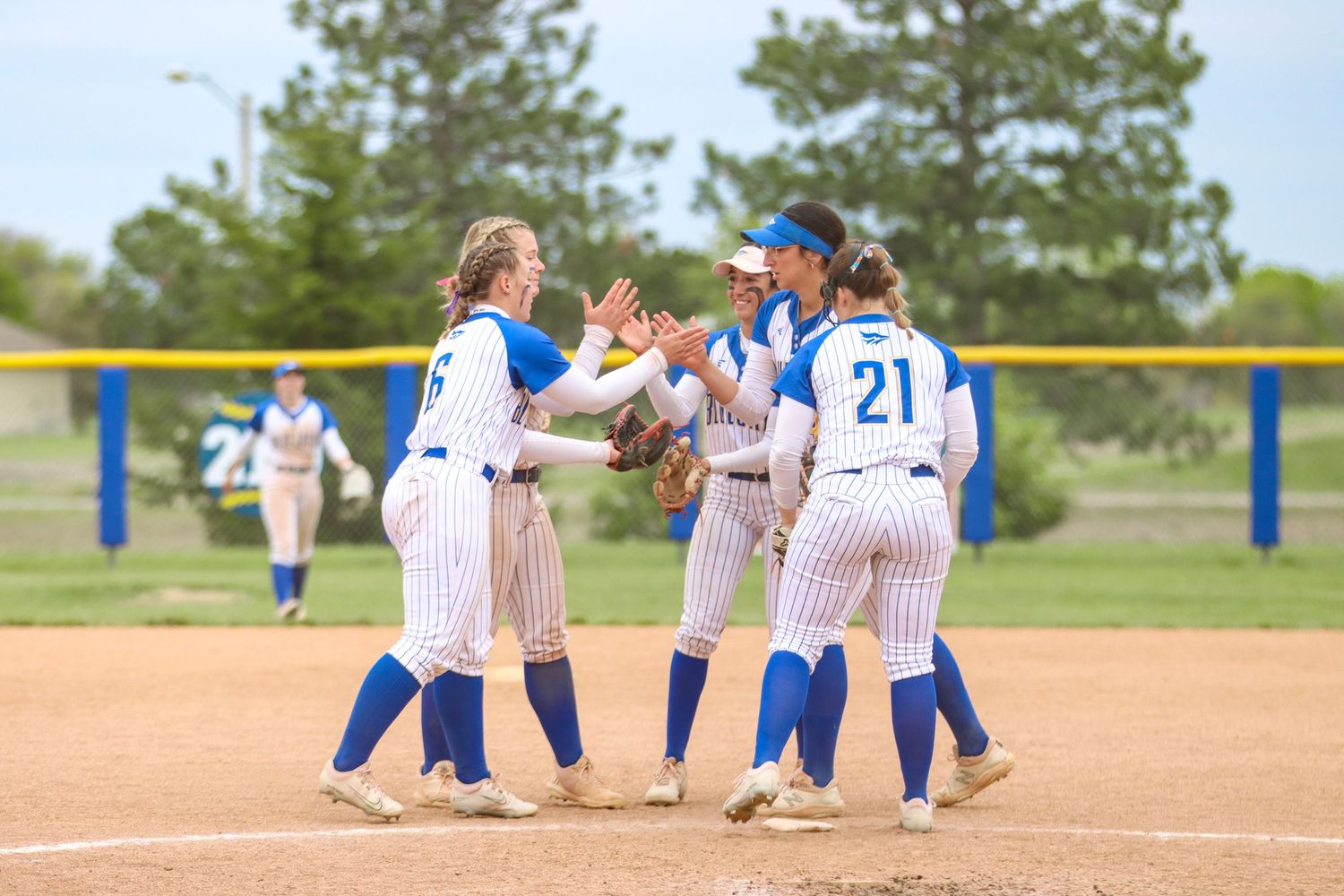 Softball team members gather for mid-game meeting on the infield.