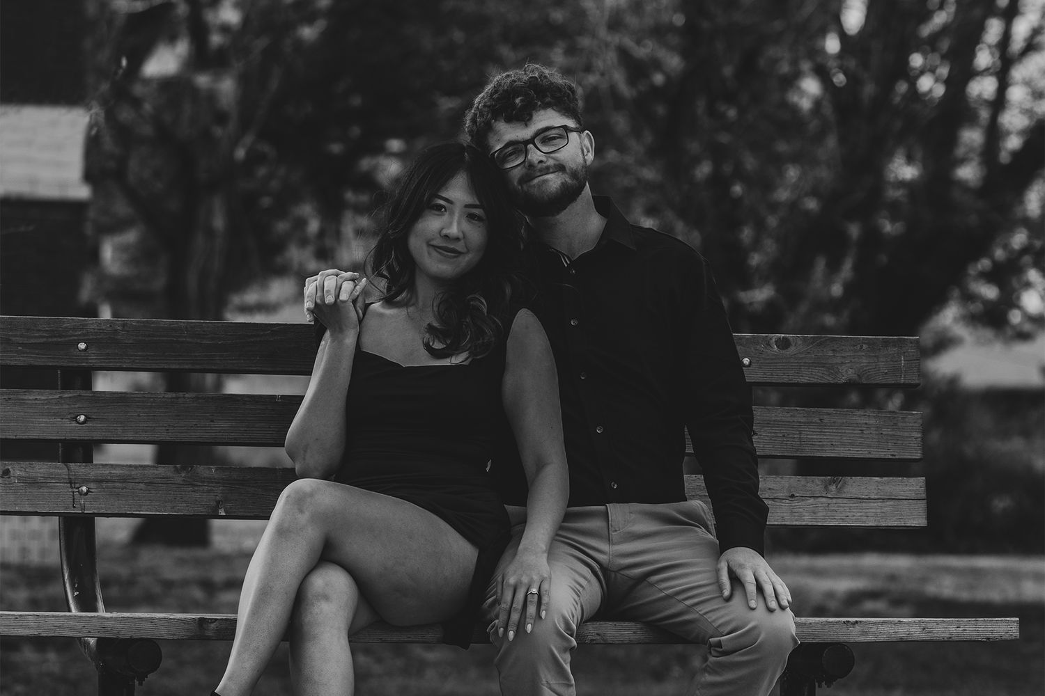 Couple sitting together on wooden bench in casual outdoor setting.