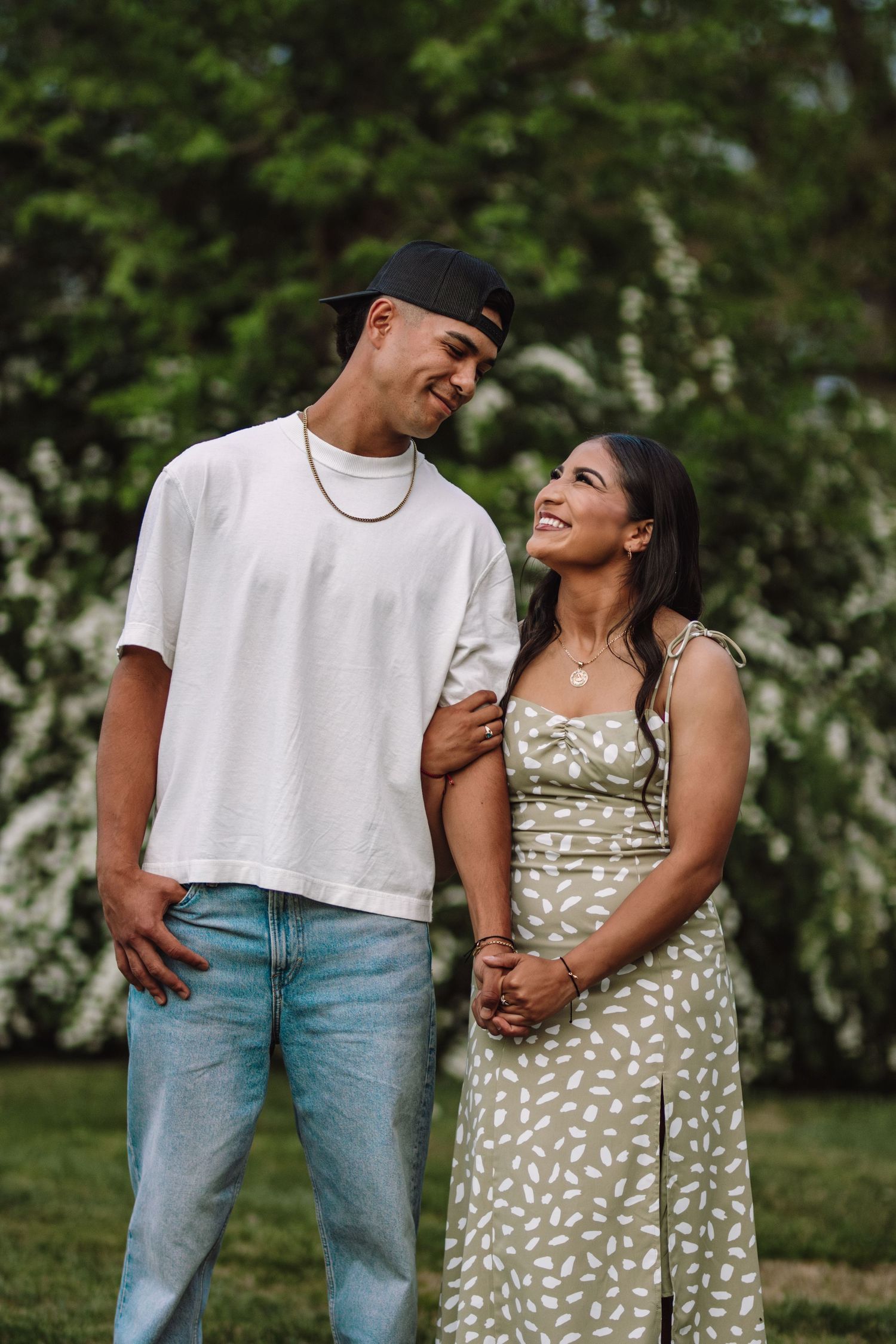 A couple shares a joyful moment together outdoors wearing a white t-shirt and floral sundress.