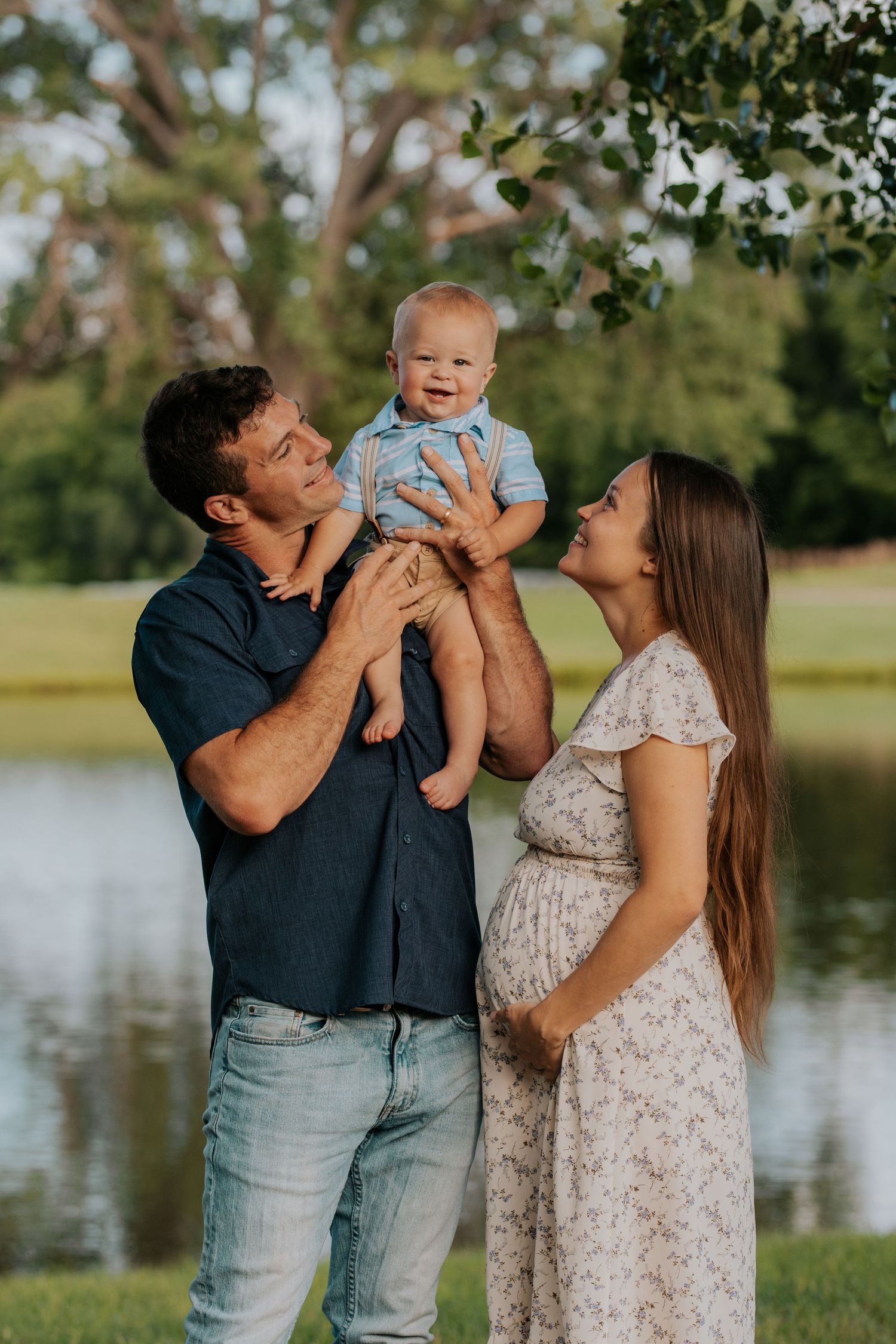 A young family shares joyful moments together outdoors by a lake on a sunny afternoon.