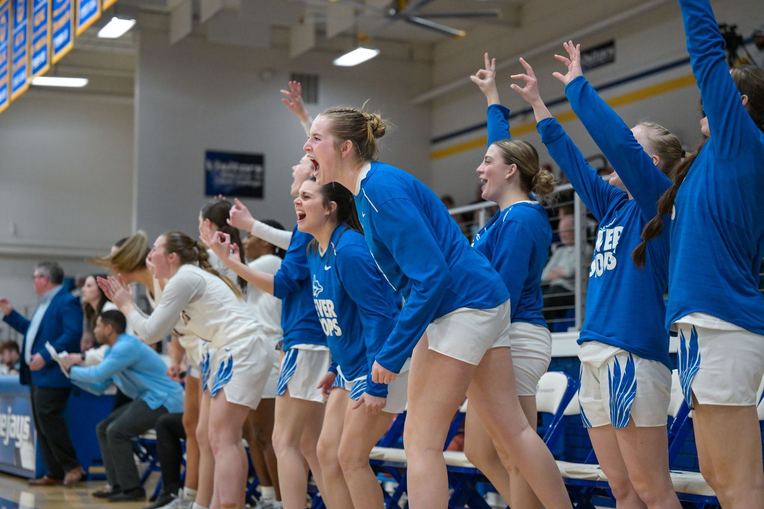 Basketball team bench celebrates enthusiastically during exciting game moment.