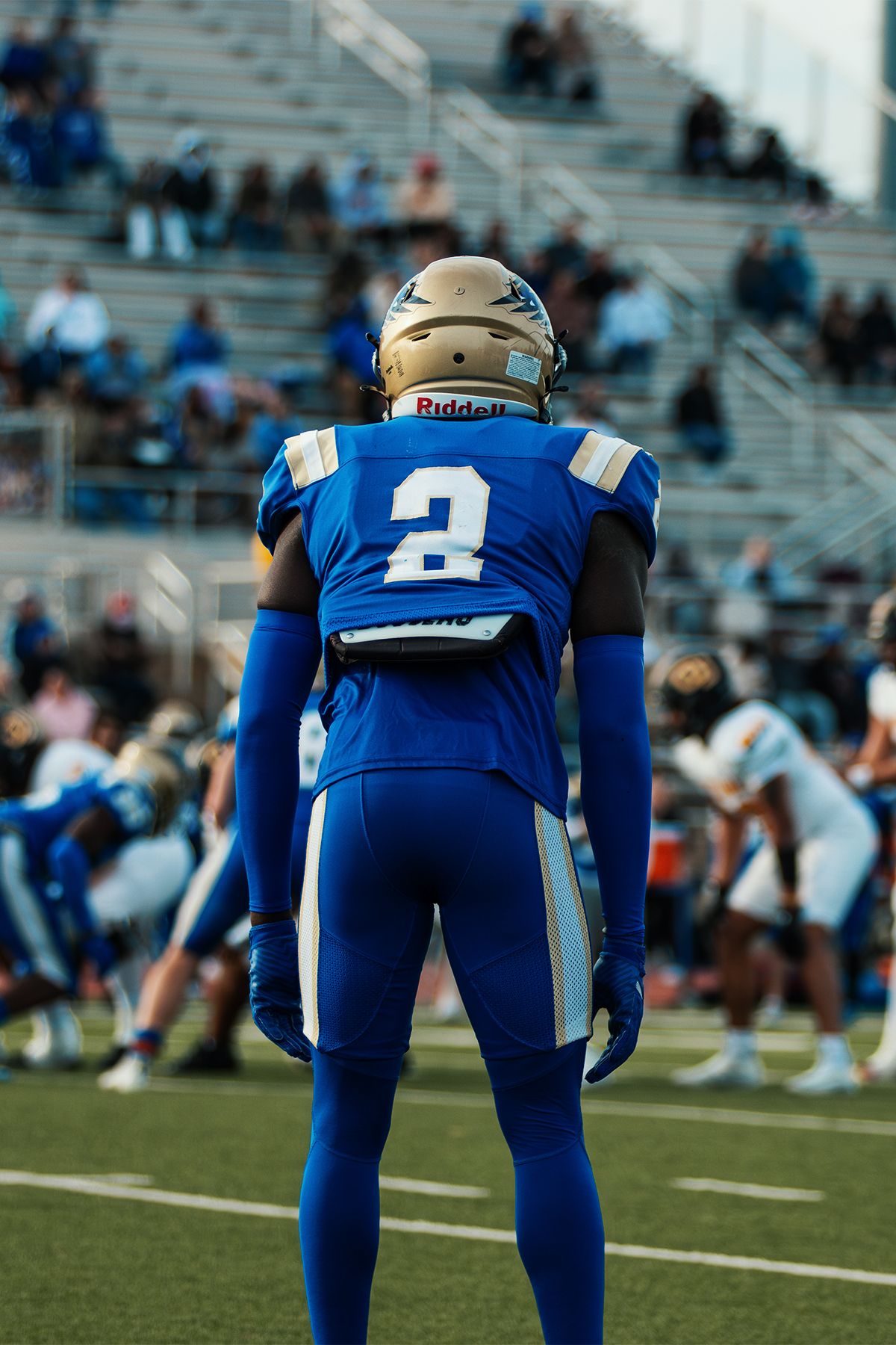 Football player in blue uniform number 2 stands on field during game.