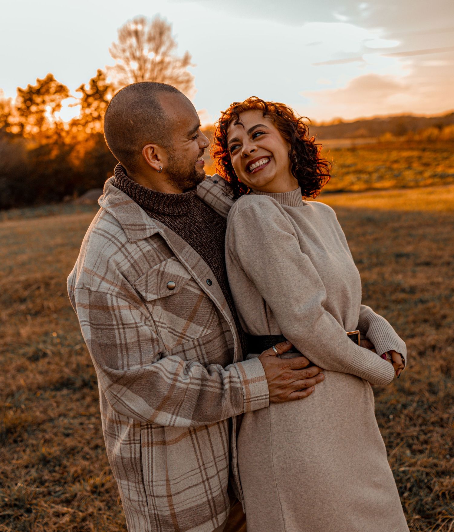 Romantic sunset photoshoot in a field with warm golden light and cozy sweaters.