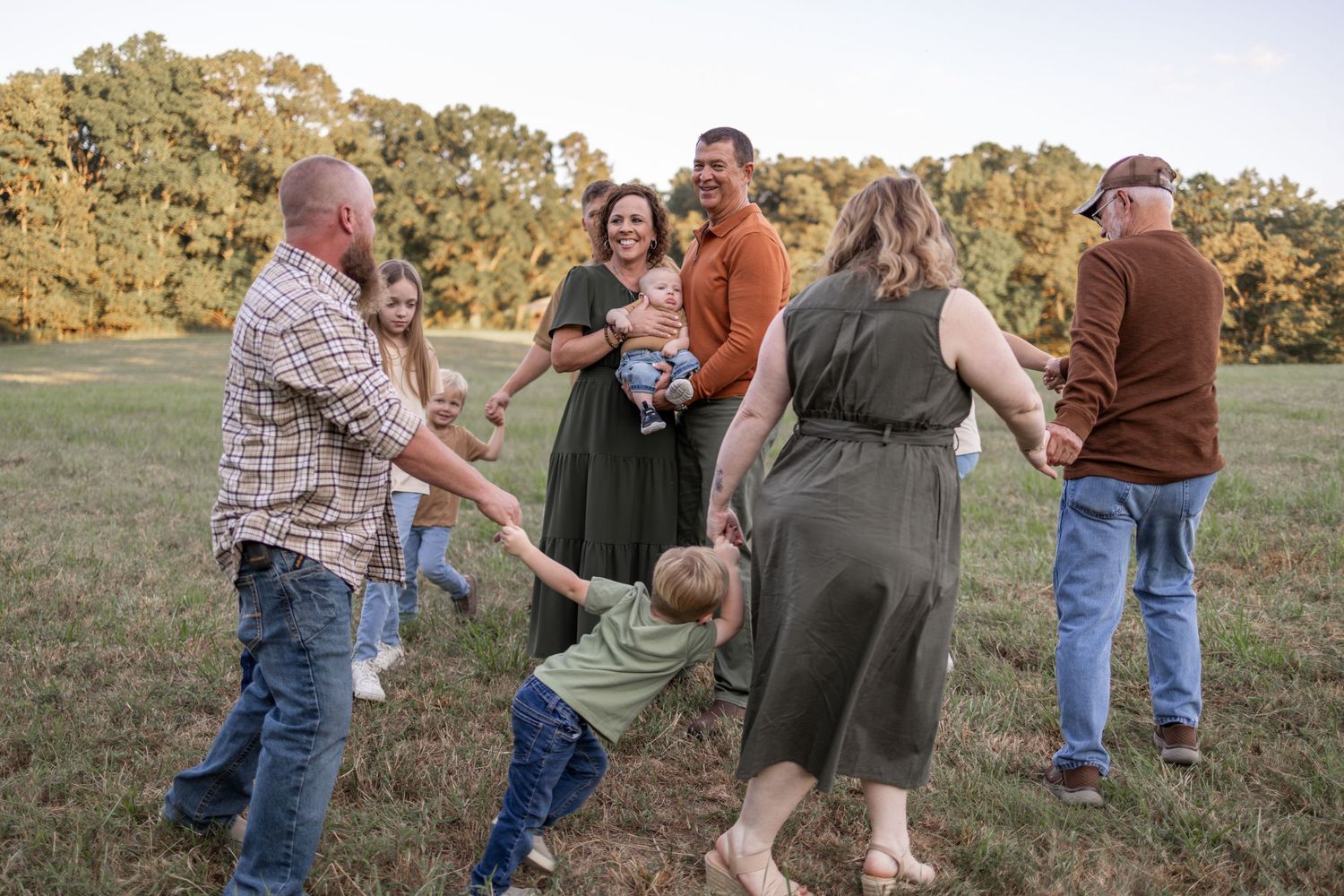 A group gathers in a sunny field for a playful outdoor photo session.