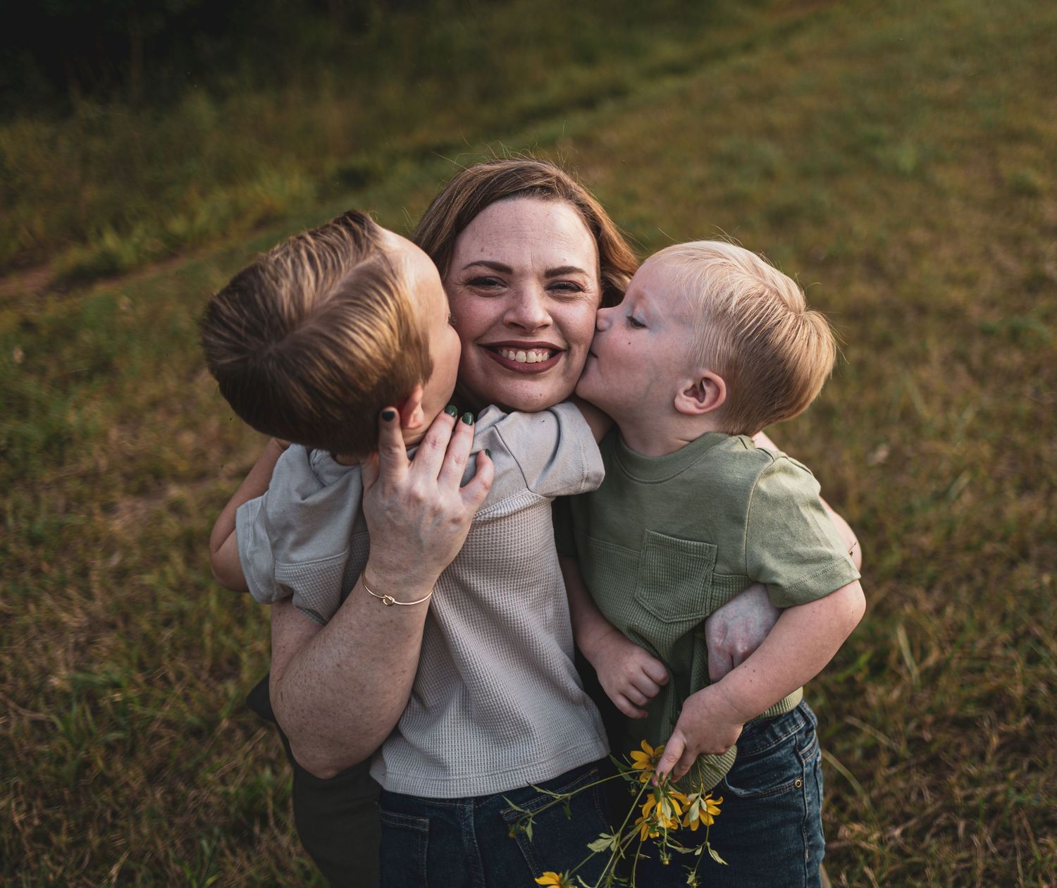A heartwarming family moment captured in a grassy field during golden hour.