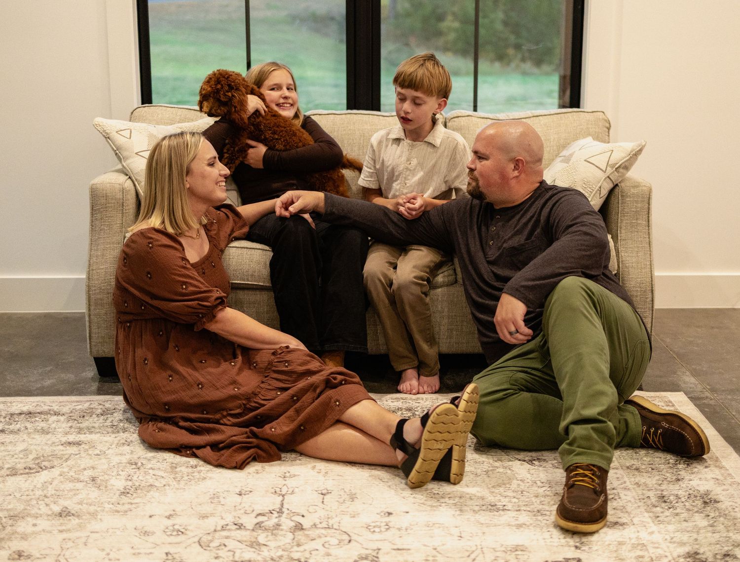 Family members relax together on a white carpet, having an intimate conversation in their living room.
