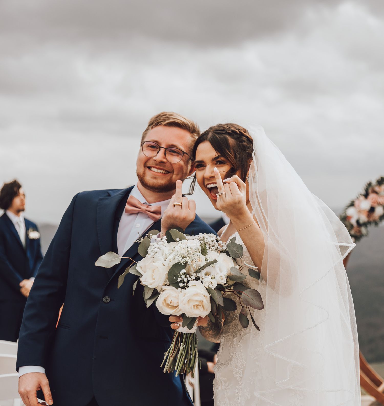 A romantic moment shared between newlyweds with a beautiful white floral bouquet against mountain backdrop.