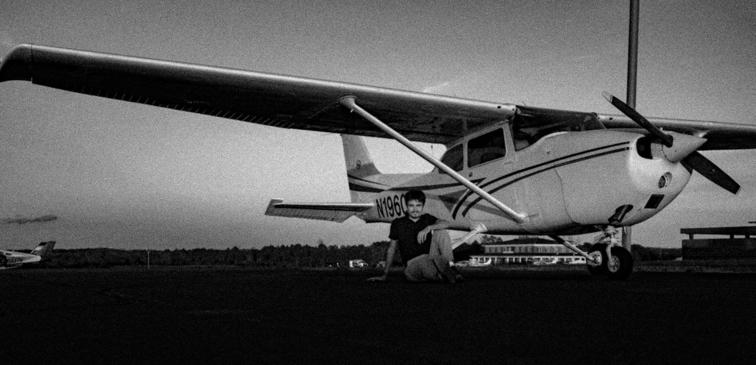 Black and white aerial view of small aircraft parked on an airfield with mountains in the background.