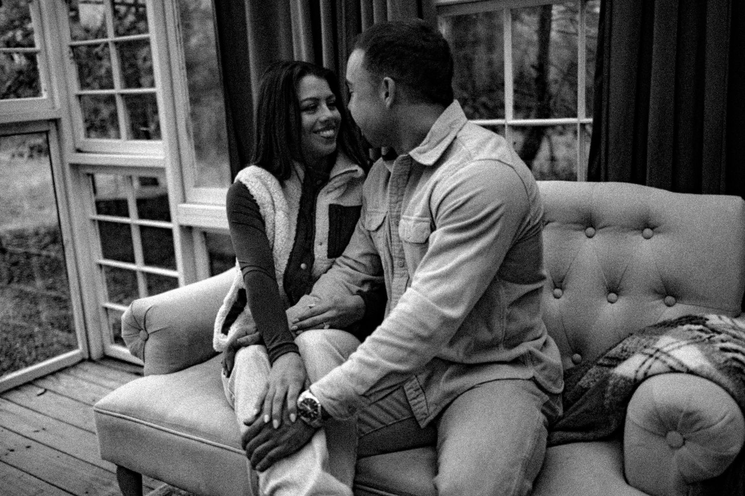 A couple relaxes together on a comfortable gray couch in a living room setting.