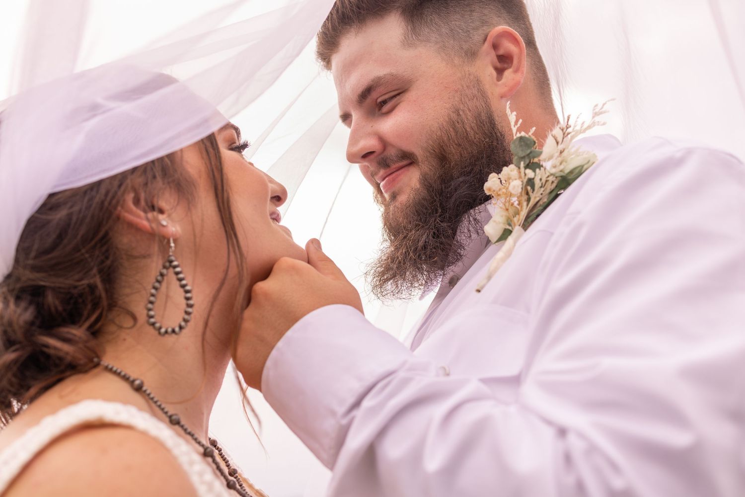 A loving couple shares an intimate moment during their wedding ceremony, with soft lighting and floral details.