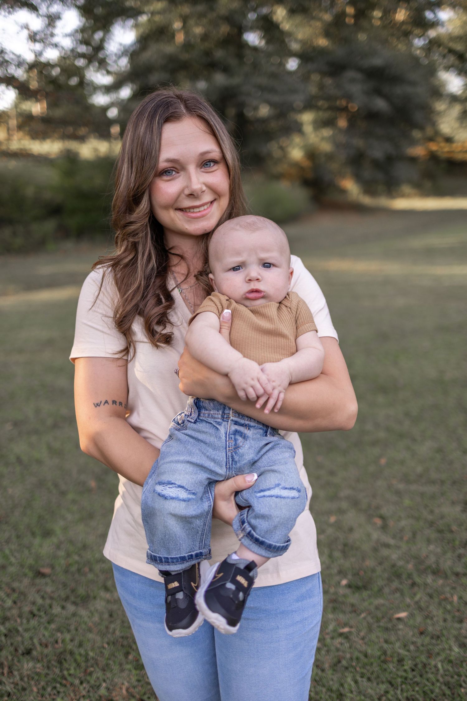 A series of outdoor photos showing a baby in denim overalls being held and cuddled on a grassy lawn.