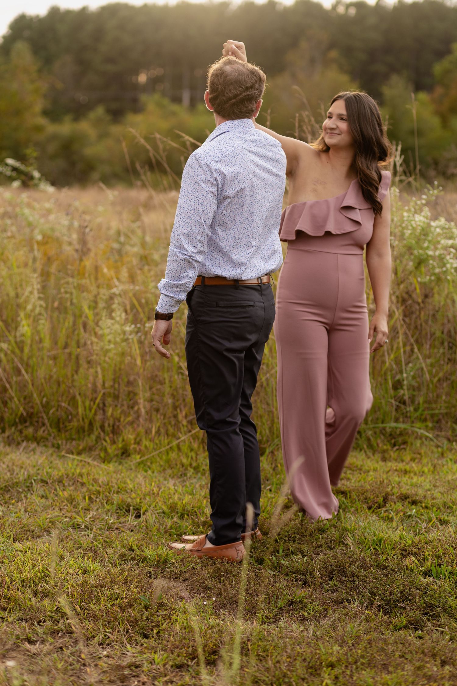 A couple walks together through a wildflower meadow during golden hour.