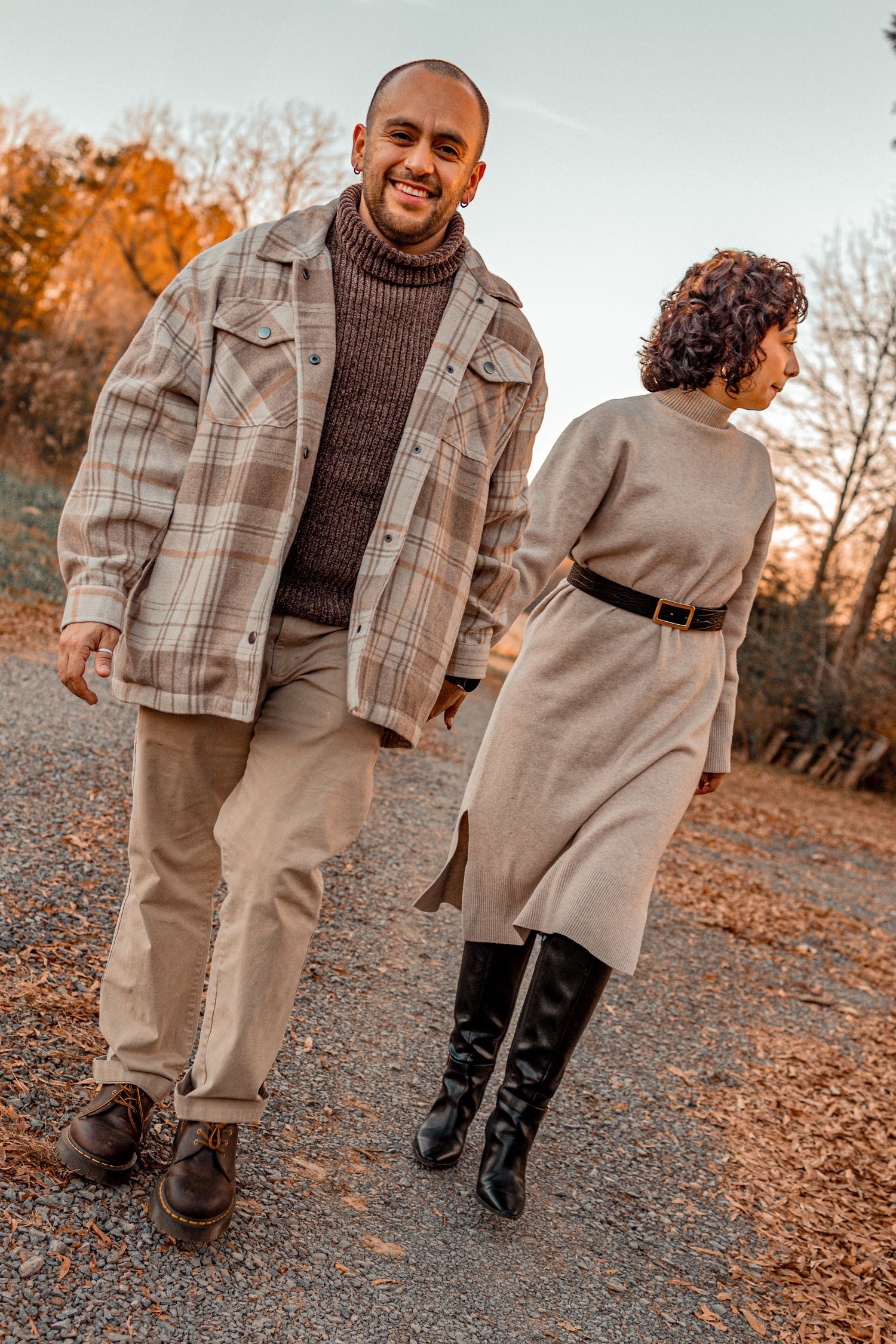 Two people walking together on a path wearing coordinated brown and beige winter outfits.