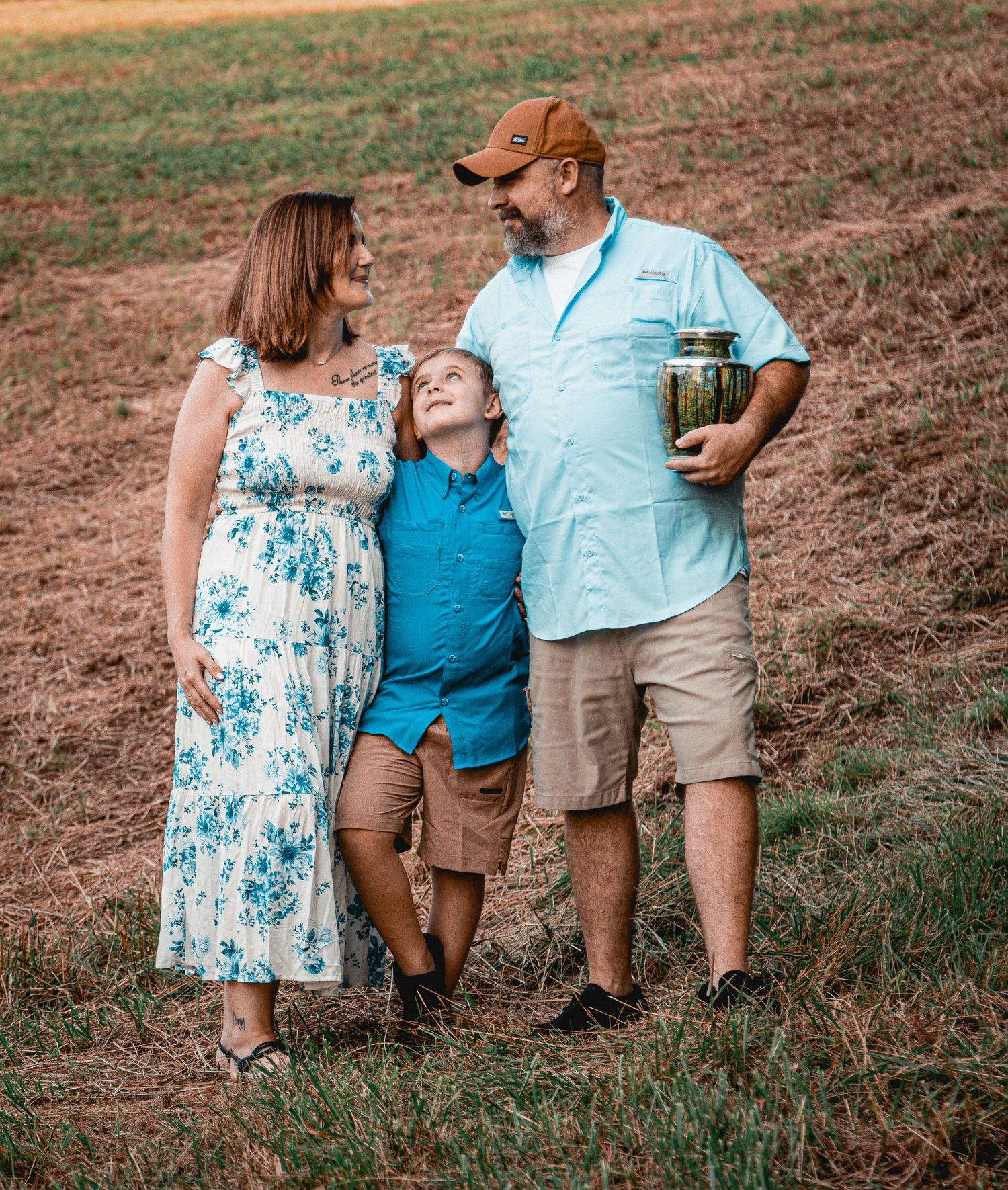 A family shares touching moments together while sitting outdoors during a photo shoot in casual summer attire.
