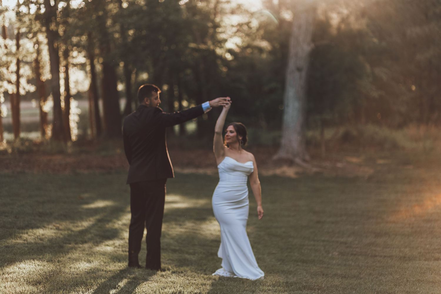 A couple shares a playful dance moment during their wedding photoshoot at sunset.