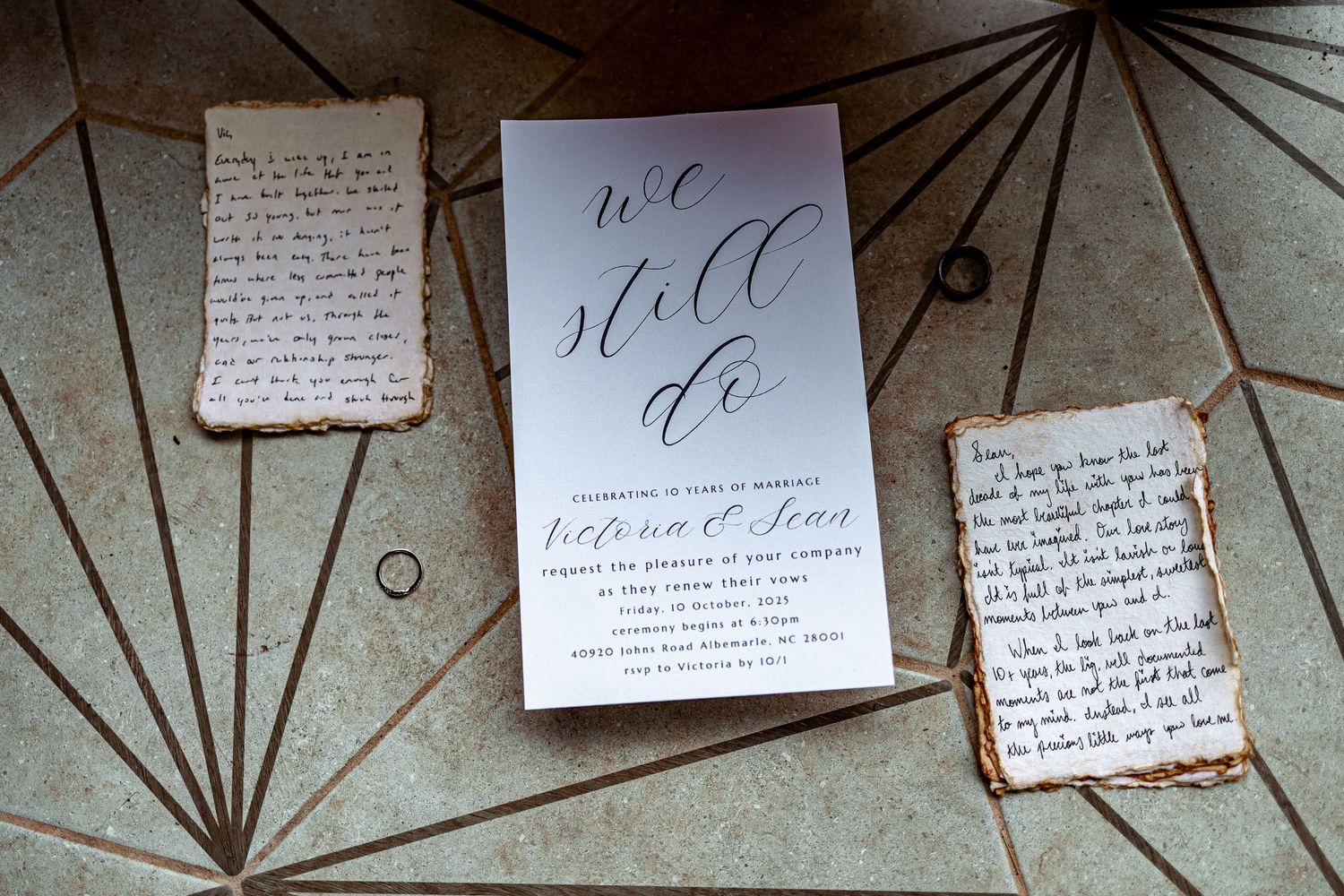 Artistic display of handwritten wedding invitations and calligraphy pieces arranged on a textured wall with geometric patterns.