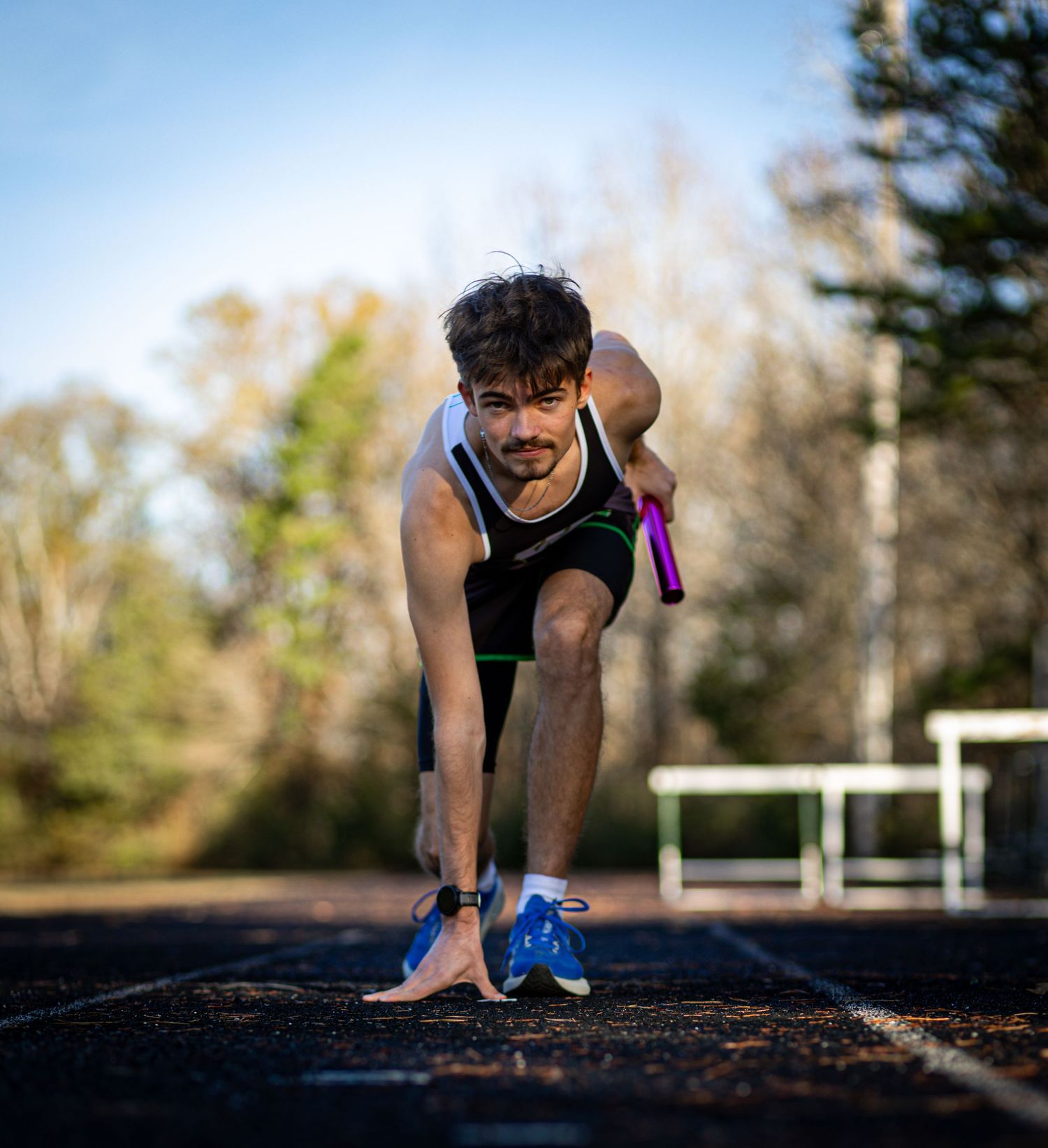 Athletic person in black workout attire stretches and prepares for exercise outdoors.