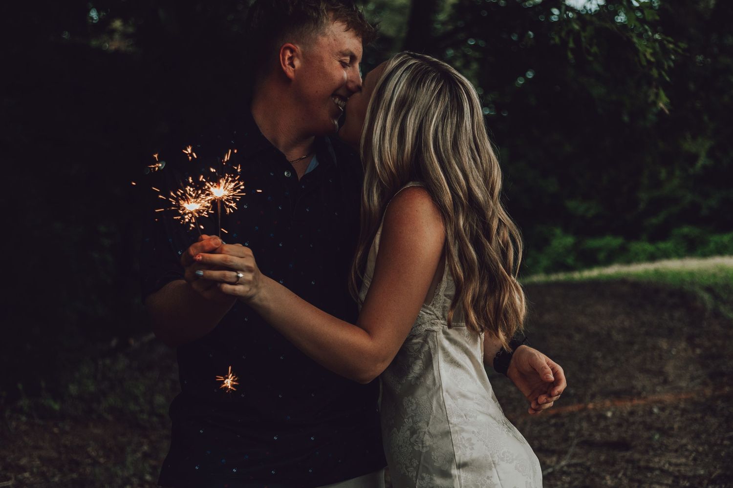 A couple holds sparklers together during a magical evening moment.