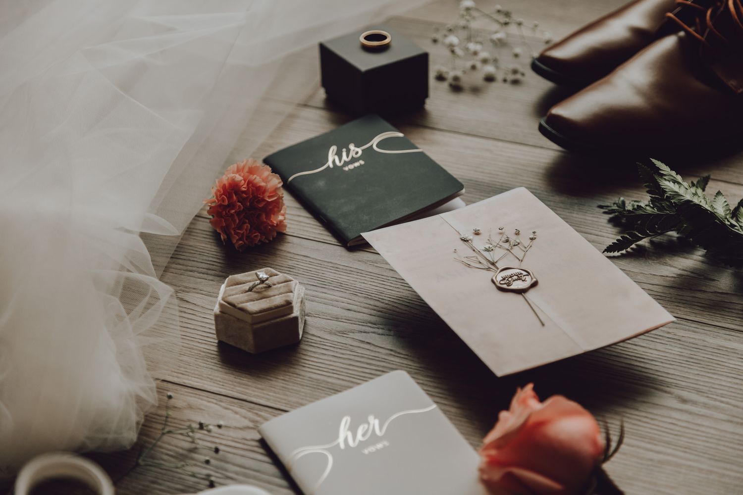 Wedding stationery flatlay with calligraphy cards, flowers and decorative elements on gray background.